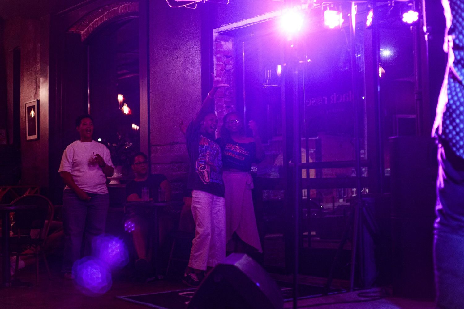 Live music performance on a dimly lit stage with purple lighting in a bar or nightclub venue.