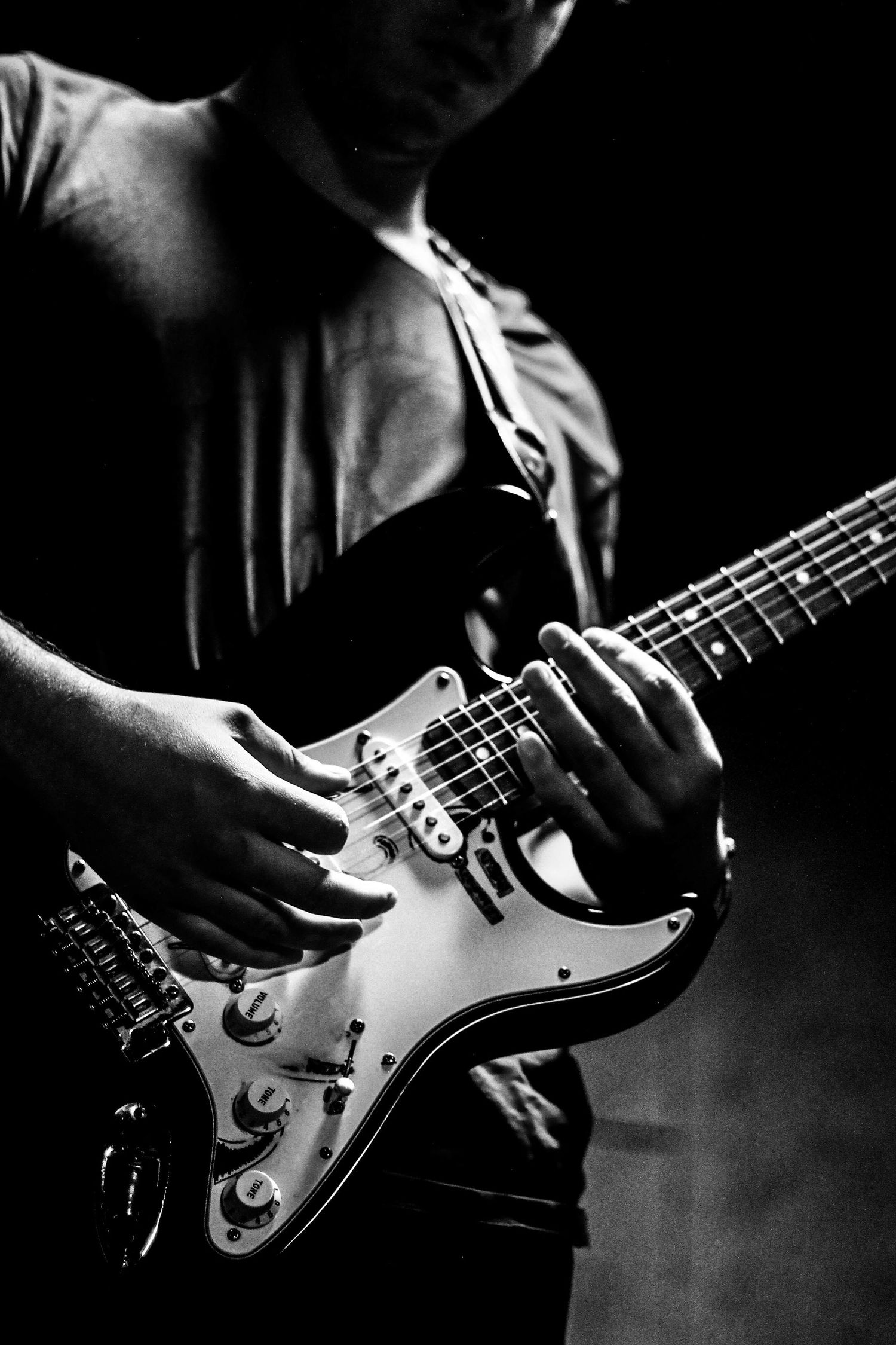 black and white high-contrast photo of hands playing guitar in Berlin