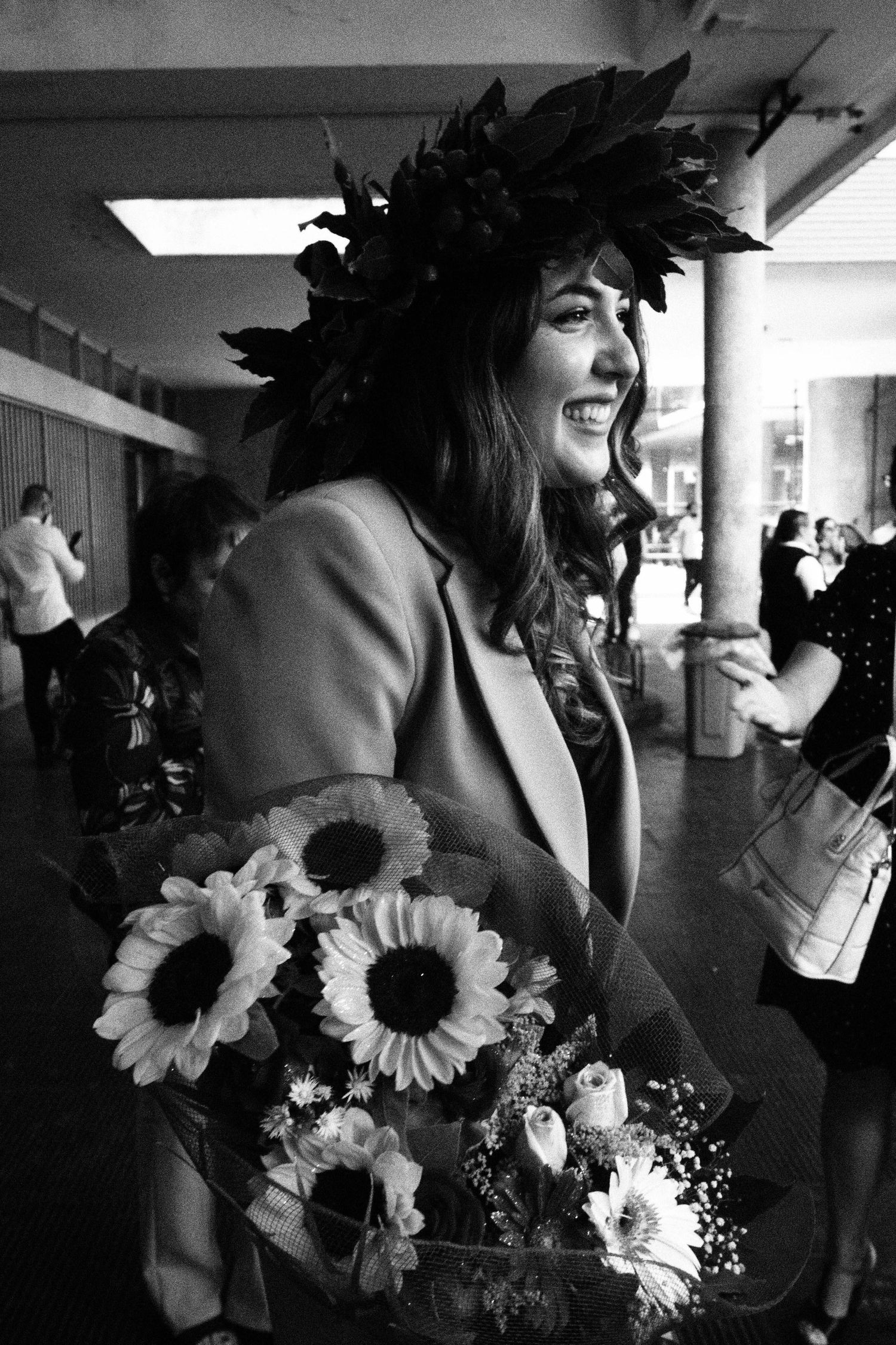 candid photo of a young female graduate with flowers and her degree, black and white, event photography