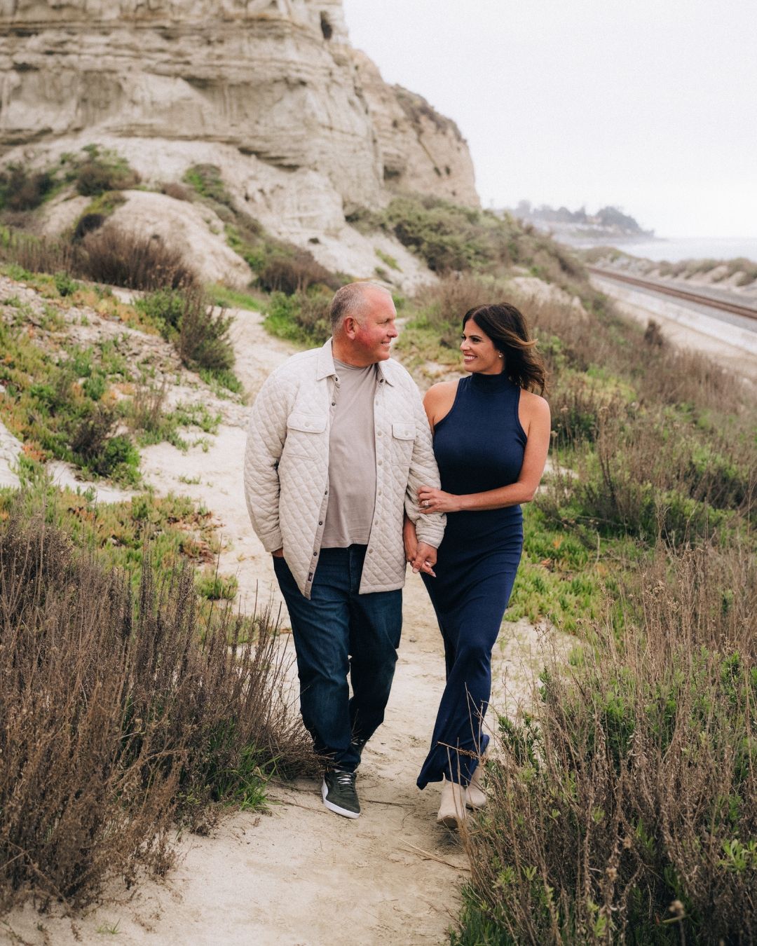 Couple posing in a warm-toned California field, romantic couples photography by Makenzie Rae Photography, Orange County California.