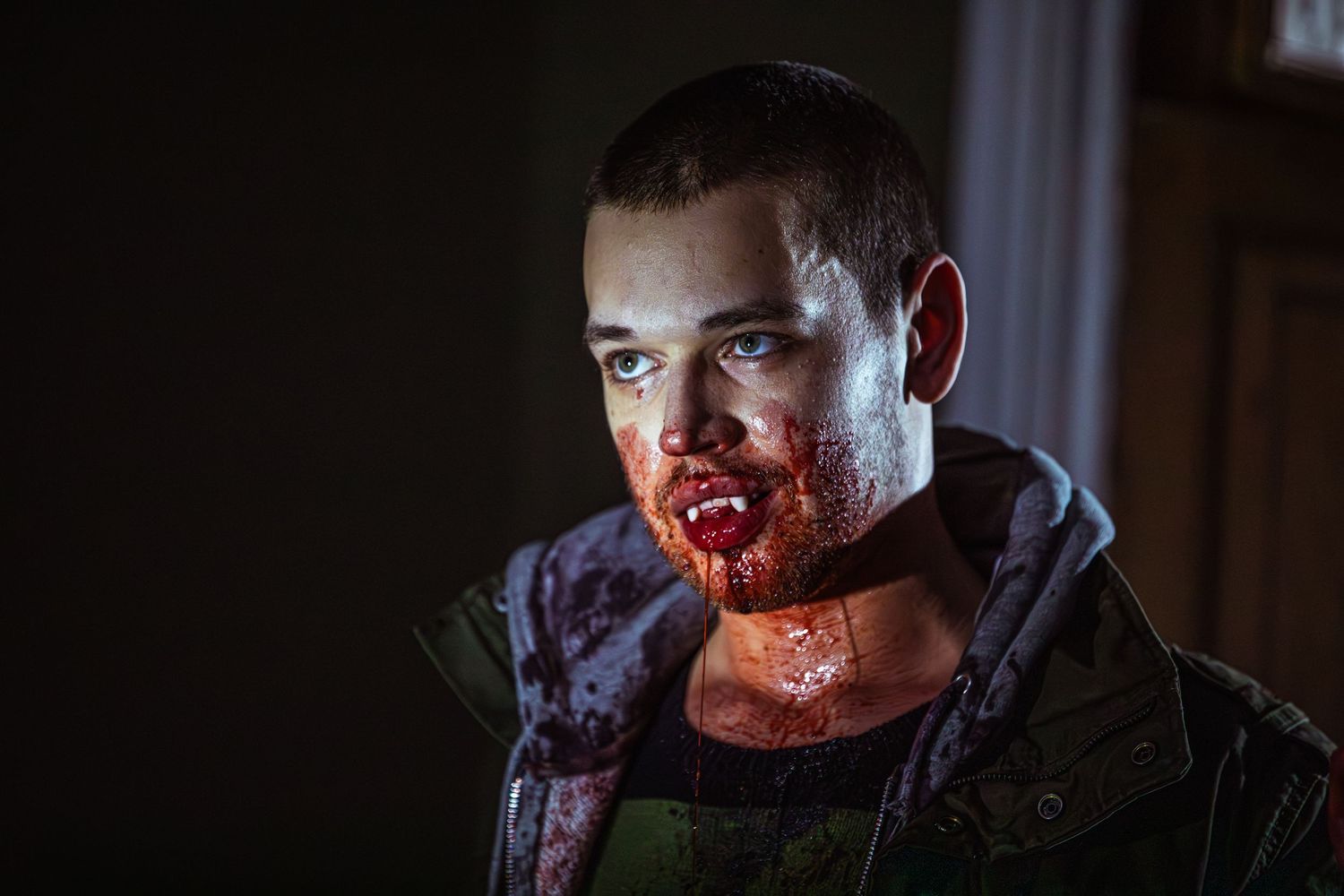 Man with bloody face in dramatic horror scene indoors.