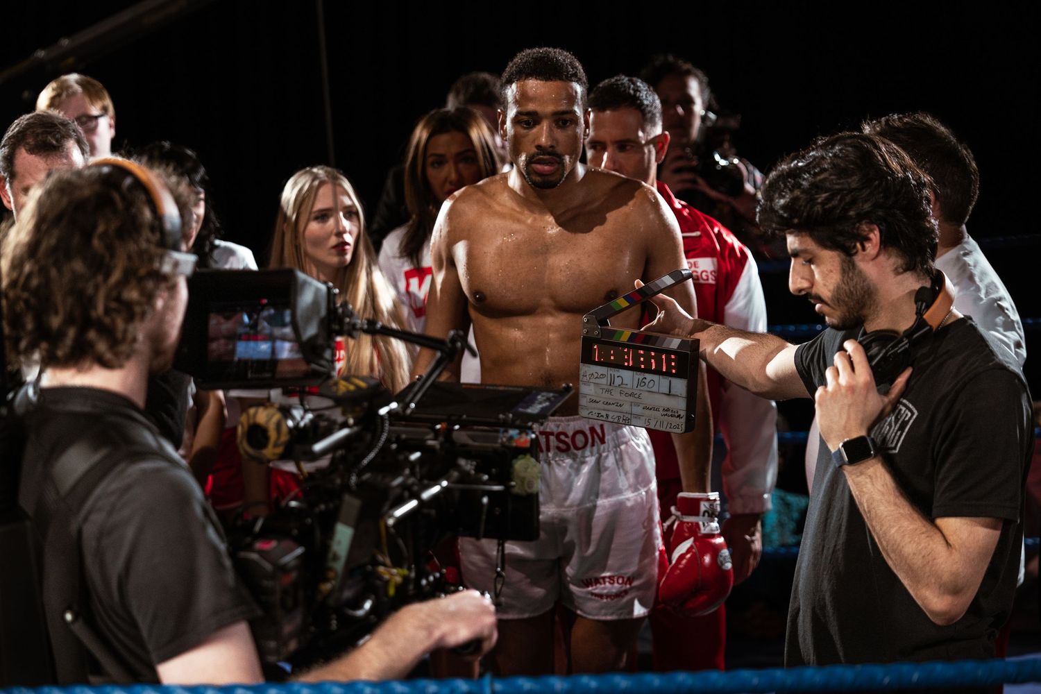 Film crew using clapperboard with boxer on set during boxing movie production.