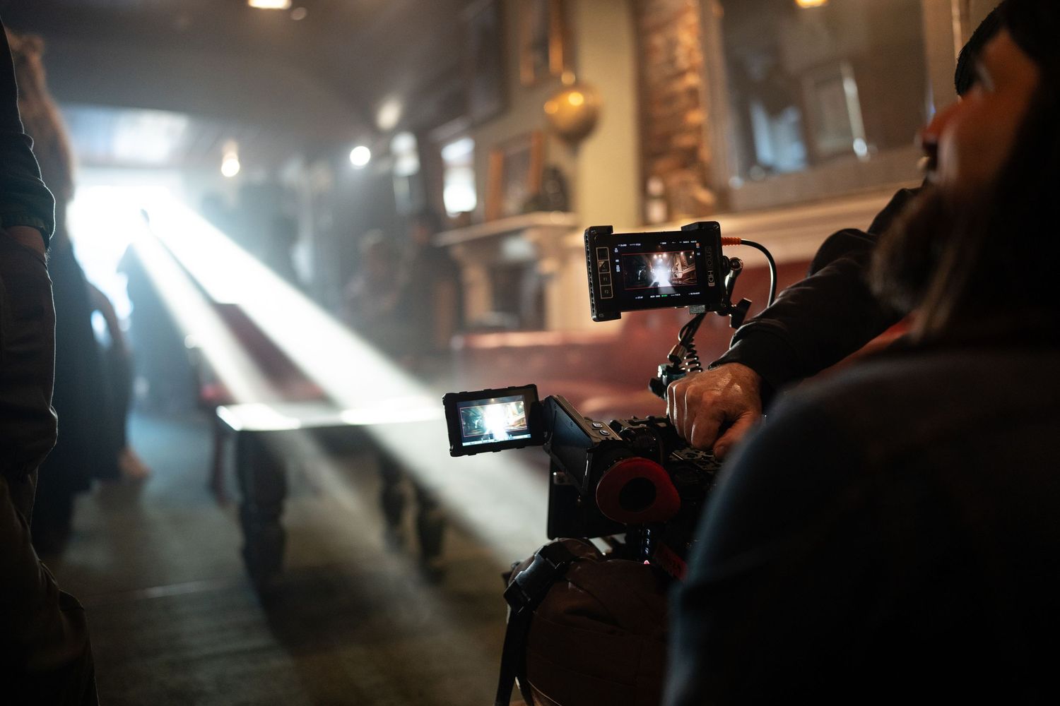 A cinematographer films a dramatic scene with a professional camera capturing a beam of light in a rustic interior.