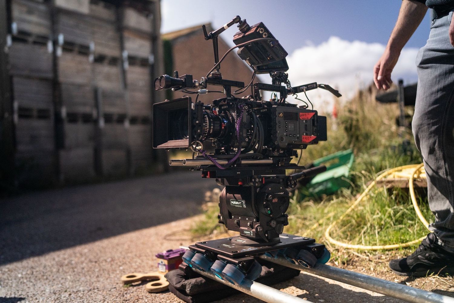 Professional film camera on a dolly track set up outdoors on a sunny production set.