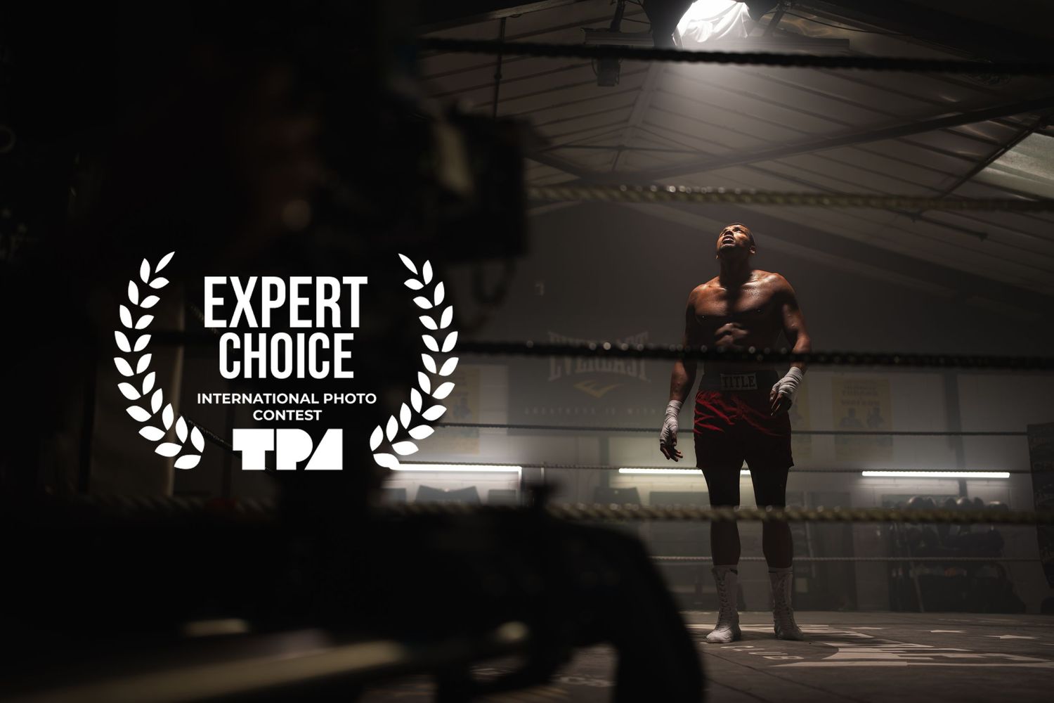 Award-winning boxing photo showing a lone fighter standing in a dimly lit ring, recognized by Expert Choice International Photo Contest.