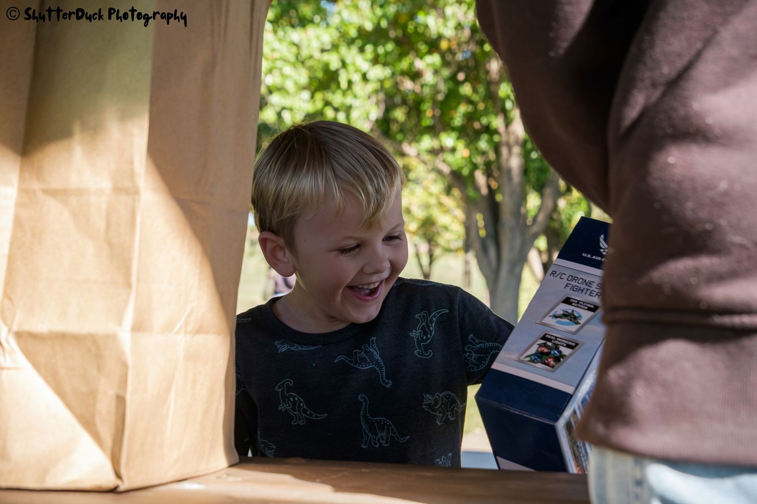 Happy young boy excited while receiving a gift at an outdoor event on a sunny day.