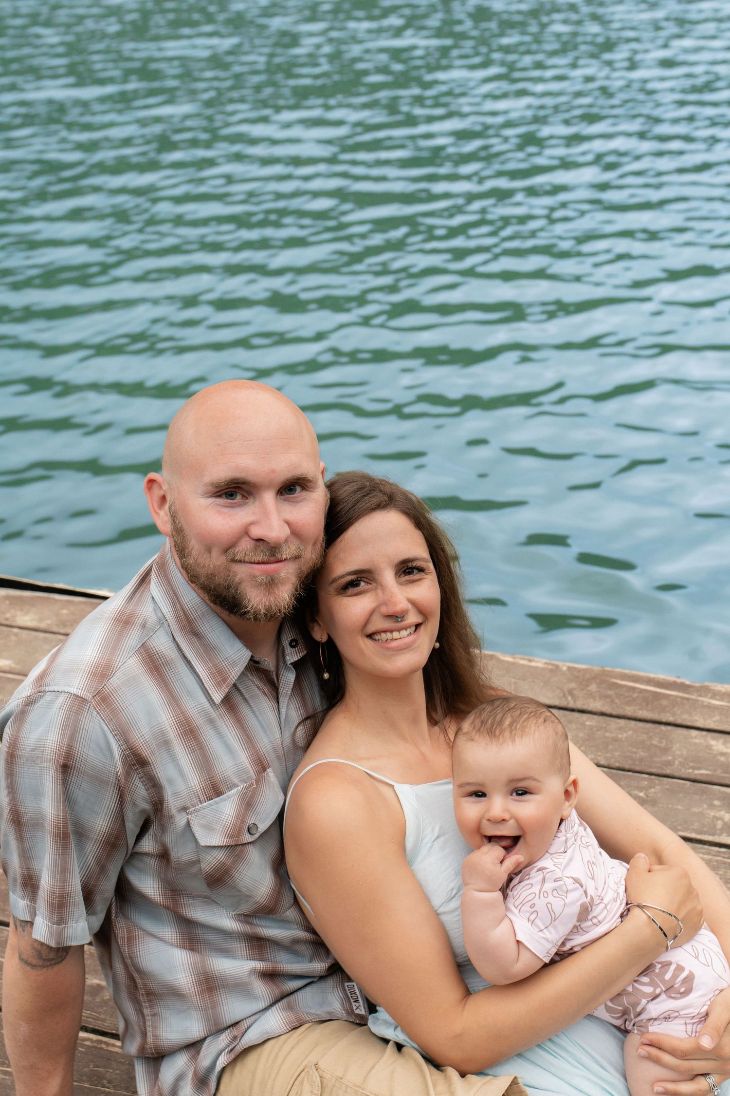 Family portrait sitting on dock with turquoise Hawaii lake water behind them.