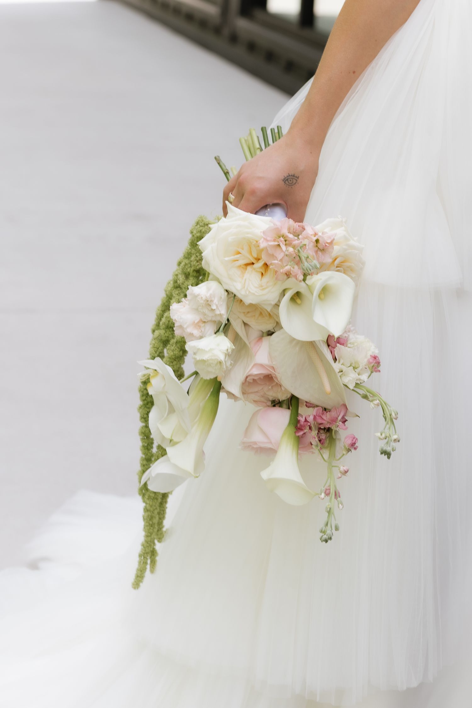 Bride holds lush cascading bouquet of calla lilies, garden roses, and pink blooms.