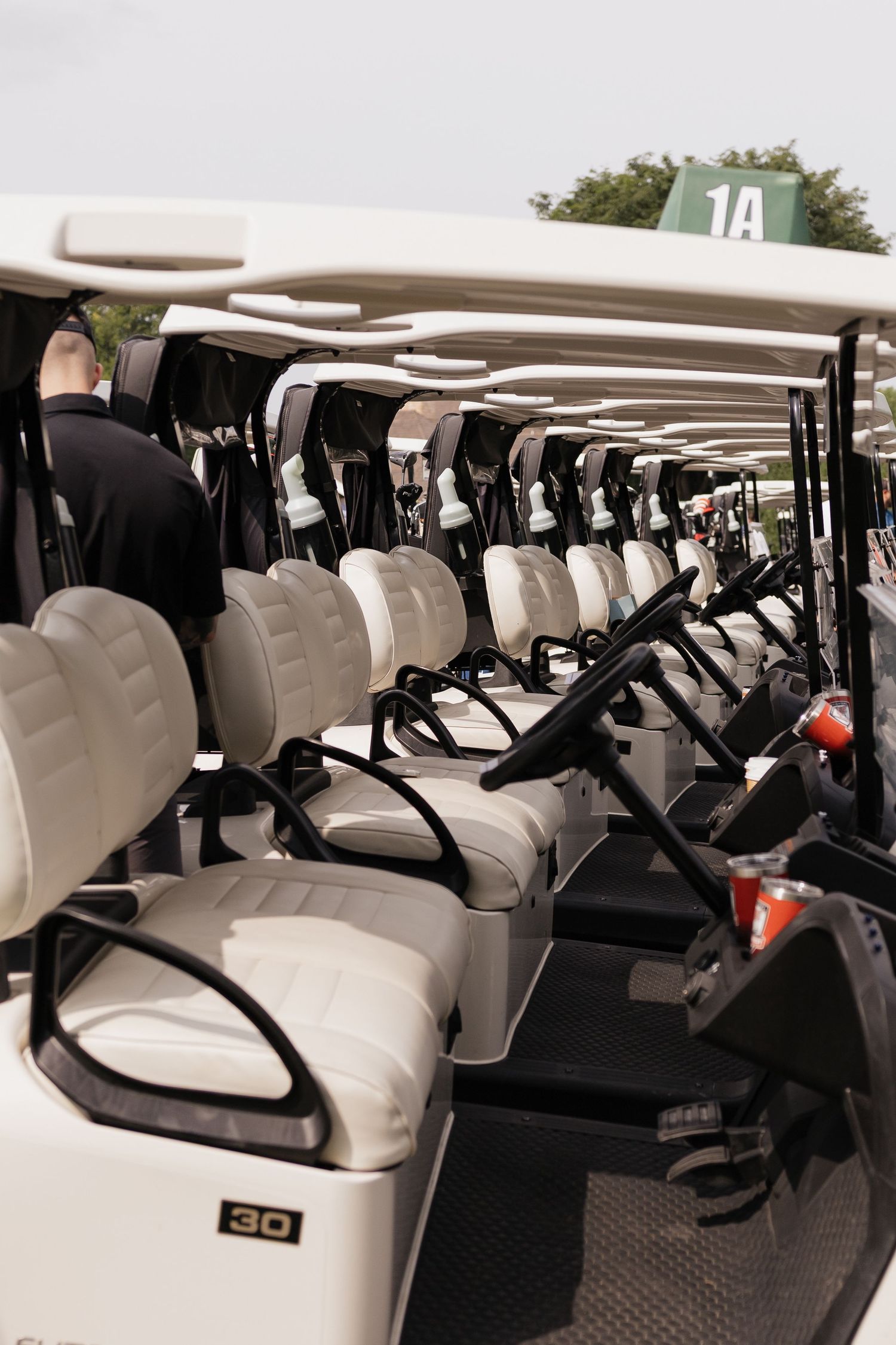 A row of white golf carts lined up neatly at a golf course, ready for players to use.