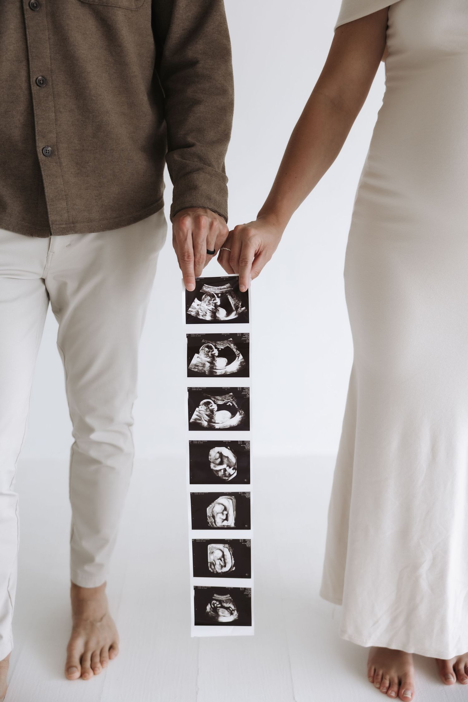 Couple holding a strip of ultrasound photos during maternity photography session.