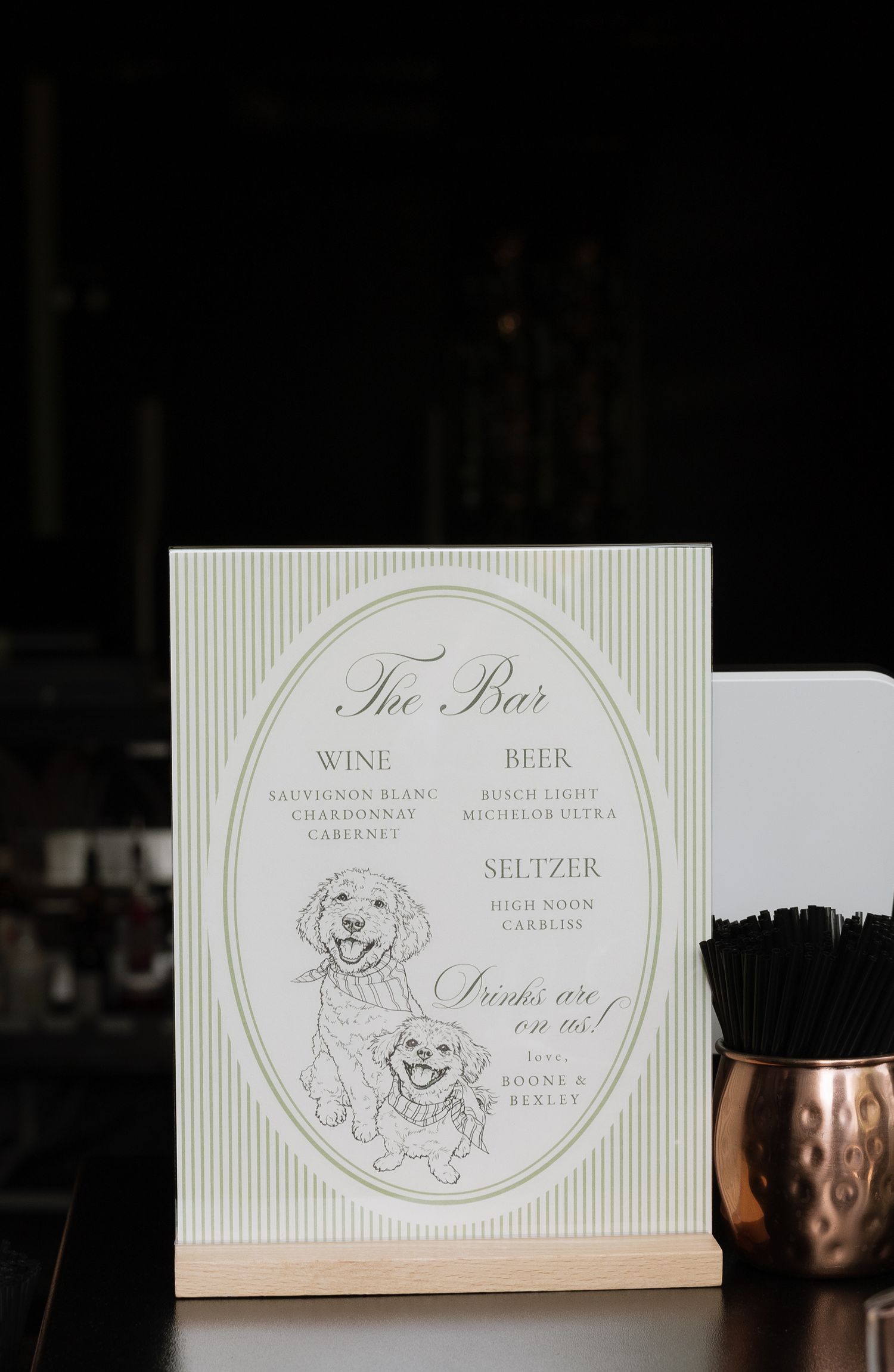 Elegant wedding bar menu sign featuring illustrated dogs, wine, beer, and seltzer options displayed on striped background.