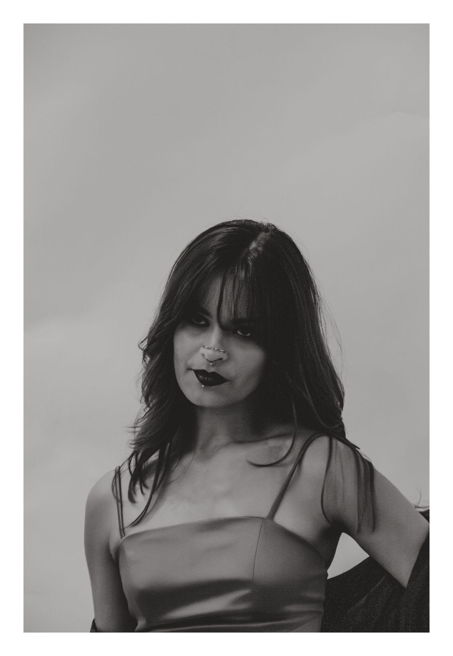 Black and white portrait of a dark-haired woman in a satin camisole with bangs.