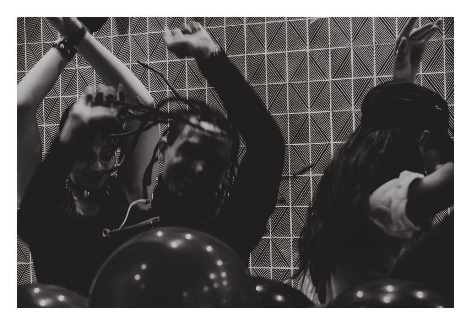 Black and white photo of performers with balloons and helmets at an energetic event.