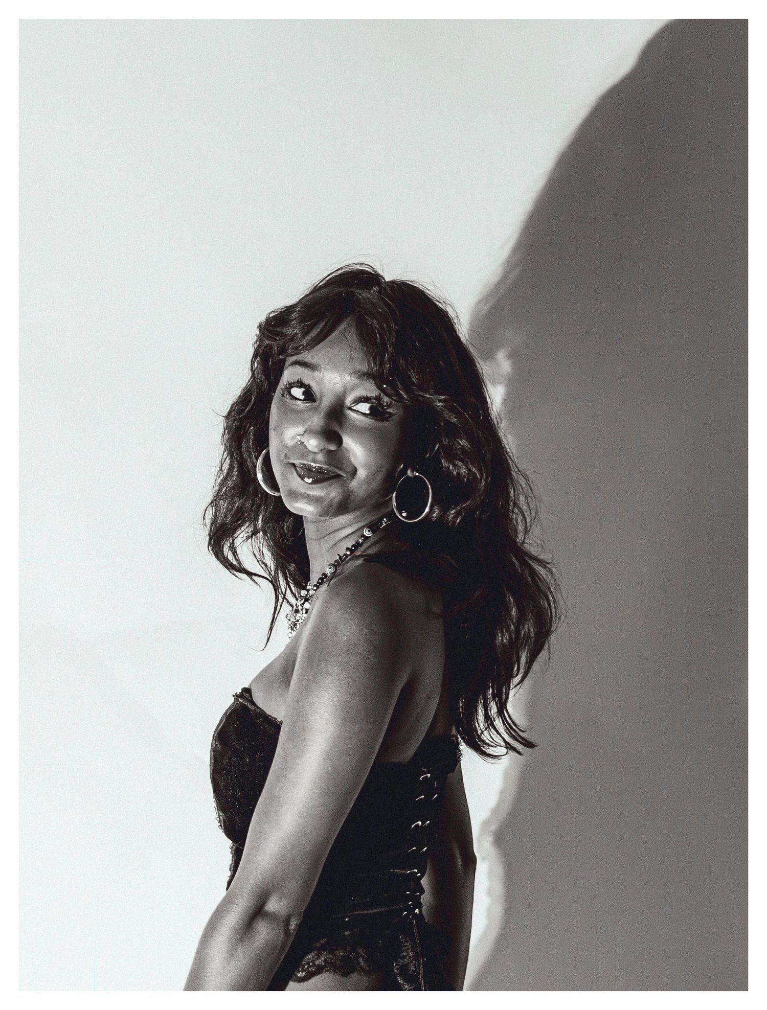 Black and white portrait of a woman in a corset top with hoop earrings.
