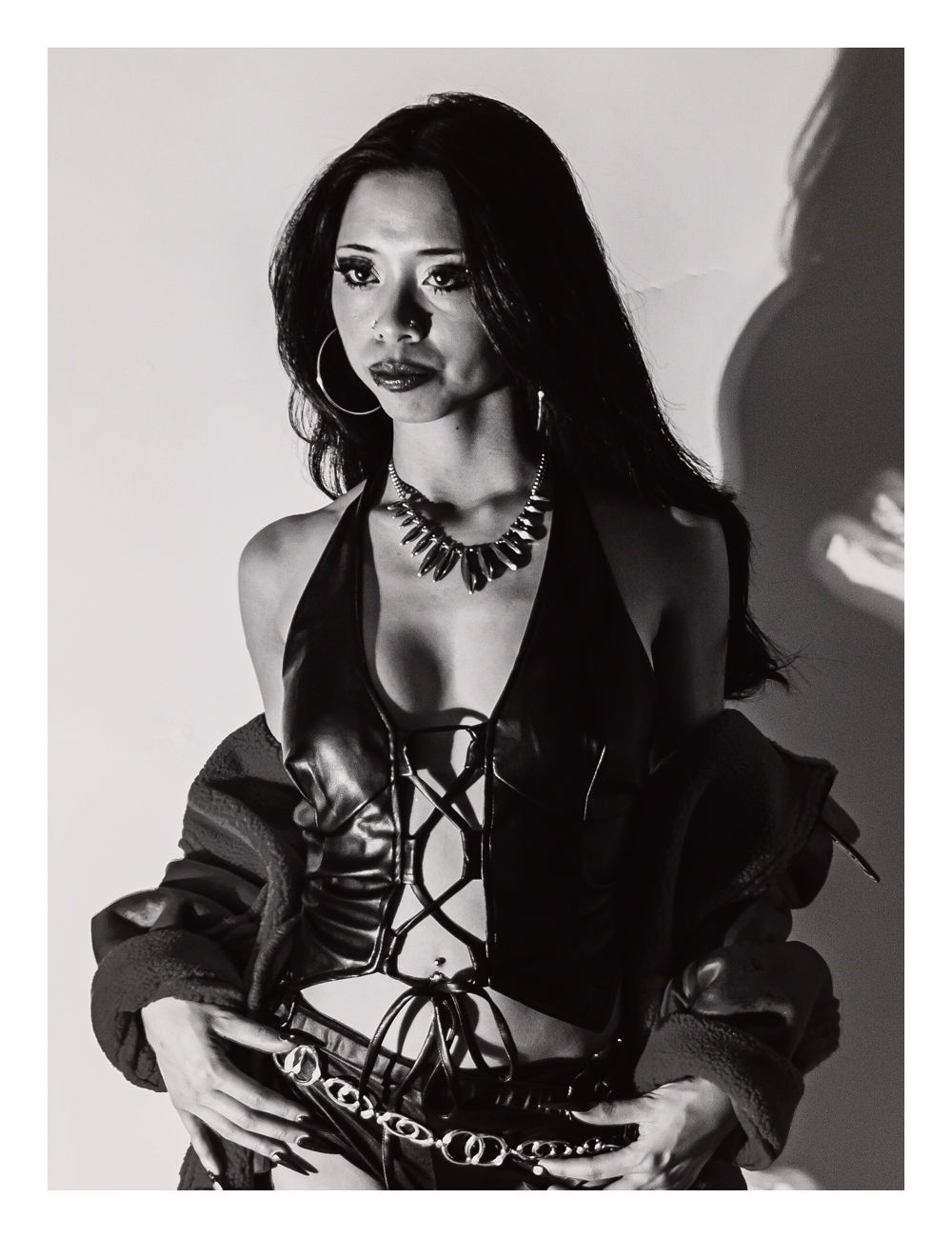 Black and white fashion portrait of a woman in a corset top with bold jewelry.
