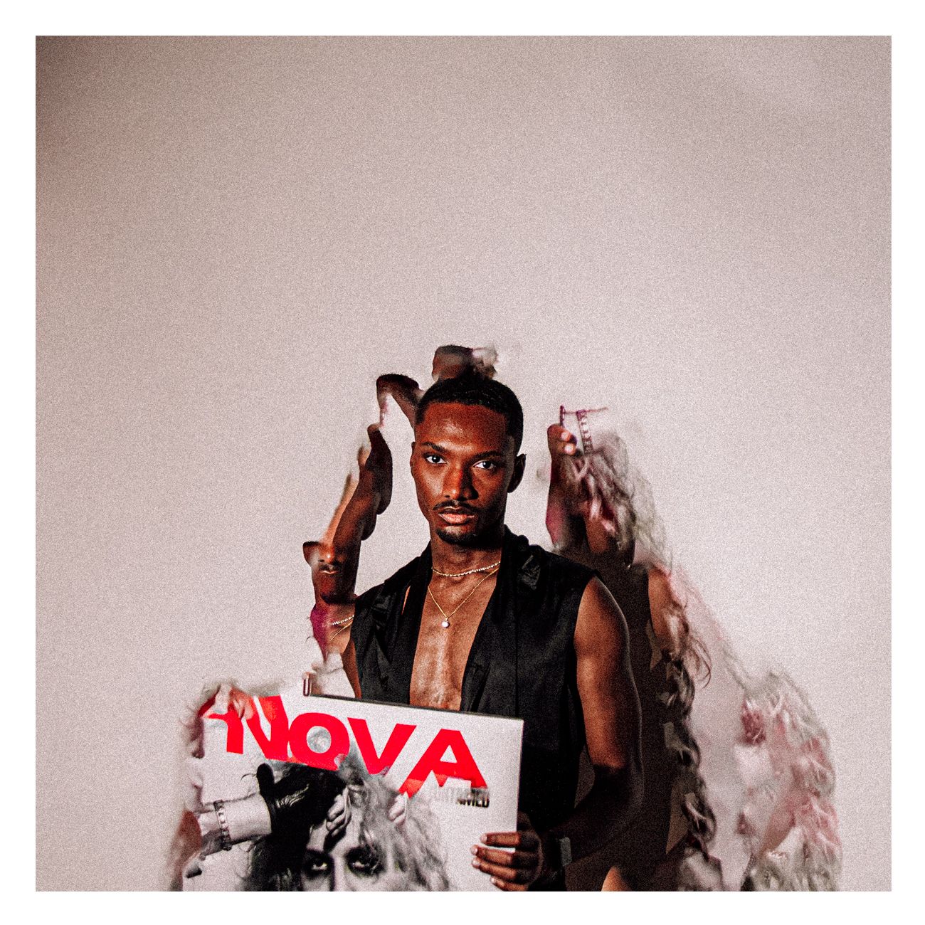 Man holds NOVA magazine cover surrounded by editorial props against neutral background.