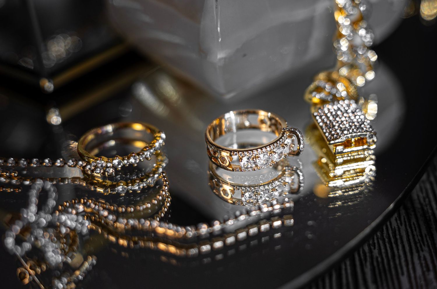 Sparkling diamond and gold jewelry pieces displayed on a dark surface with dramatic lighting.