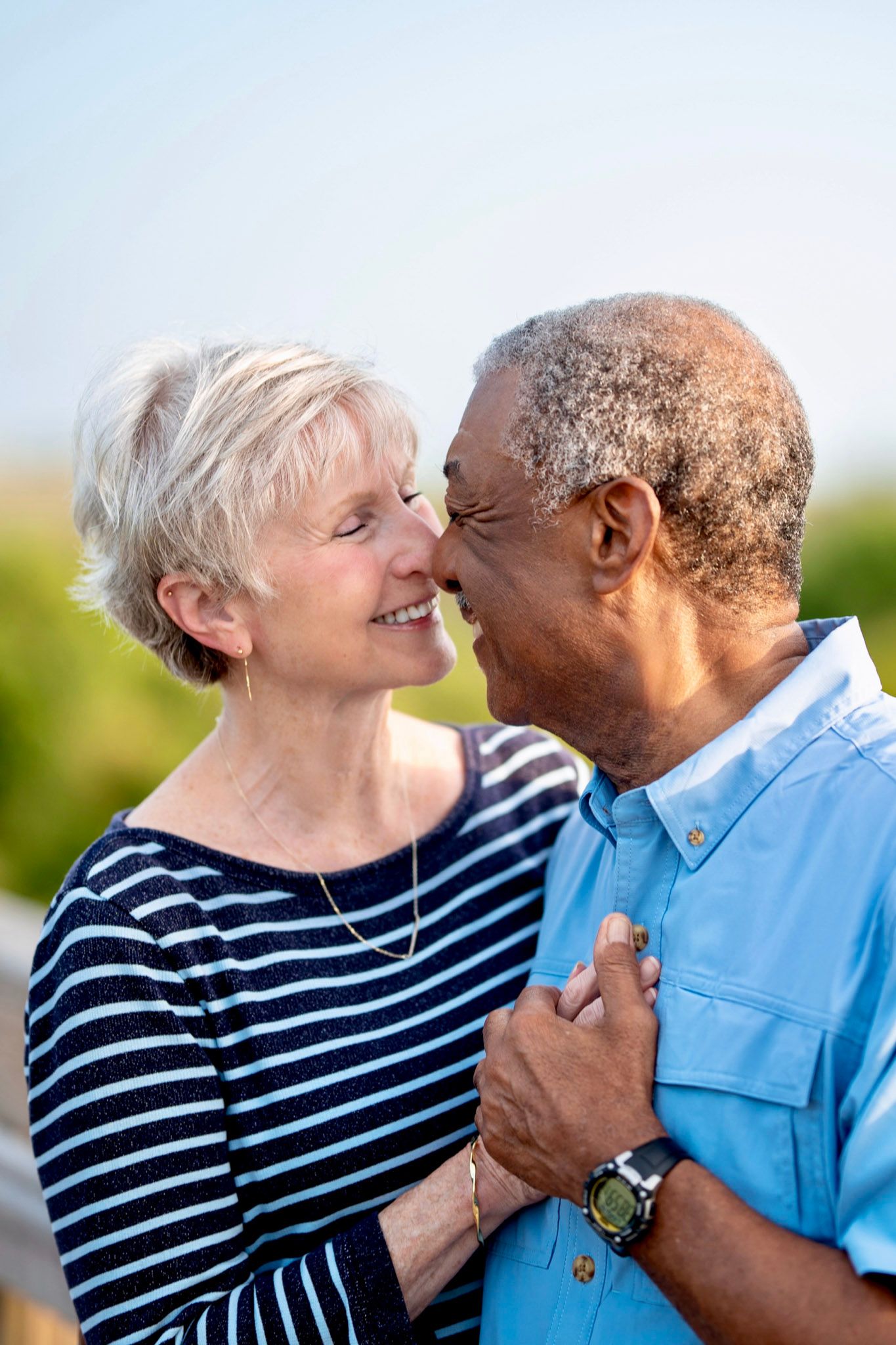 Senior couple in loving embrace sharing an intimate moment outdoors.