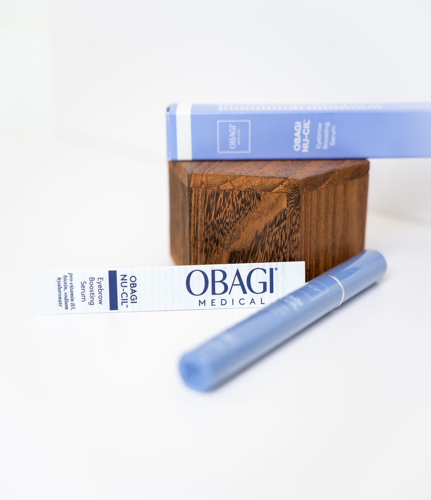 Obagi skincare products including a blue package and applicator displayed on a white surface with wood accent.