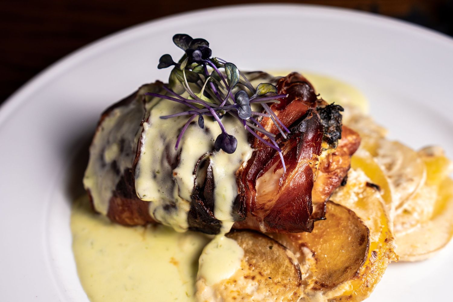 Elegant plated dish with purple microgreens and cream sauce drizzle.