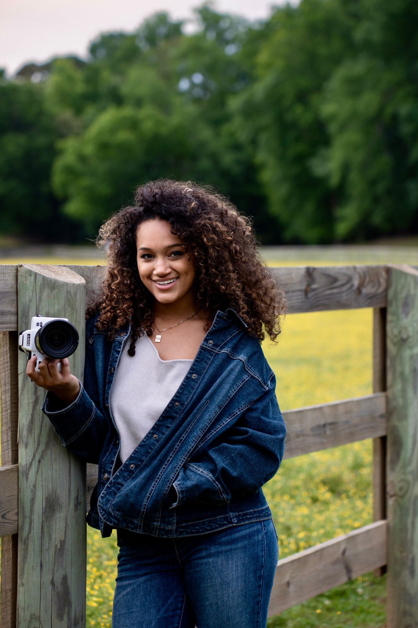 Professional photography session with denim jacket against rustic wooden fence.