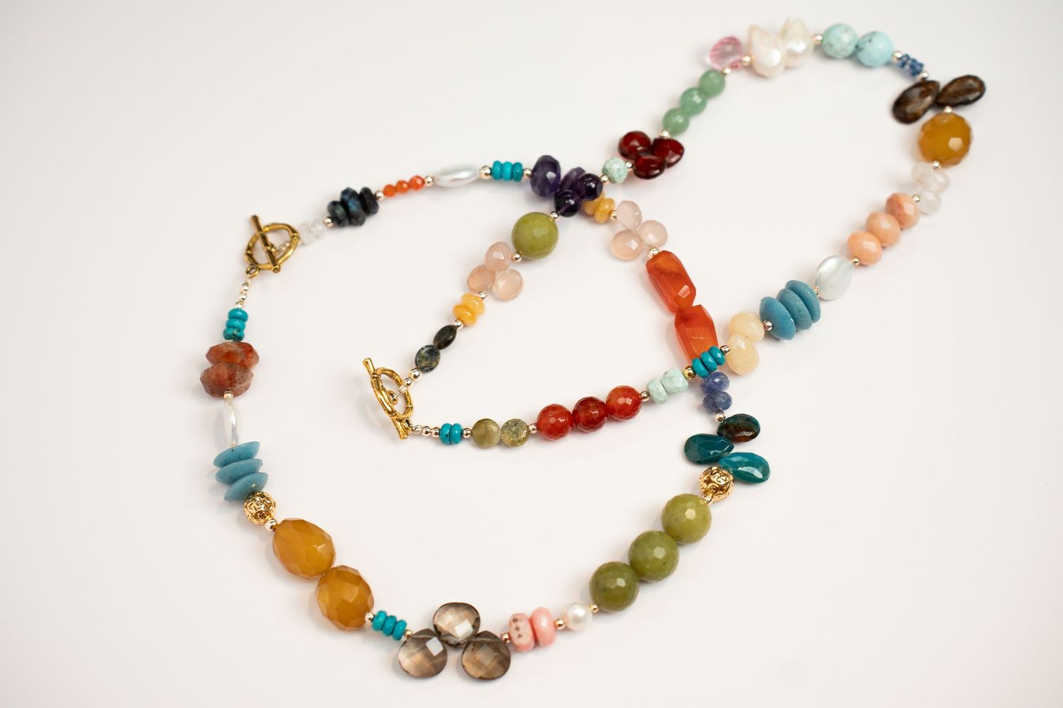 Colorful beaded necklace featuring mixed gemstones and crystals arranged in a curved pattern.