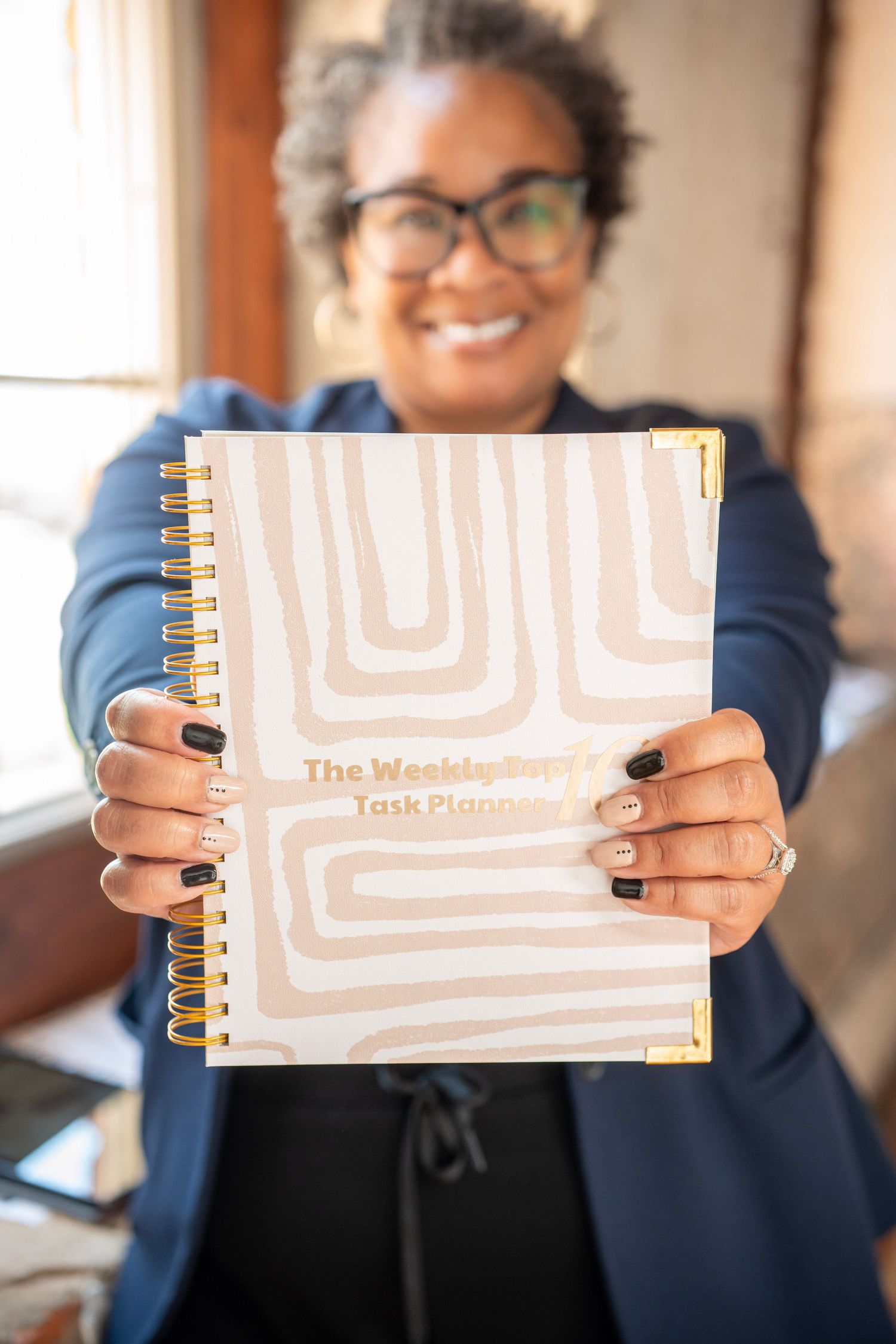 Professional displaying a spiral-bound planner or notebook with beige geometric pattern design on the cover.