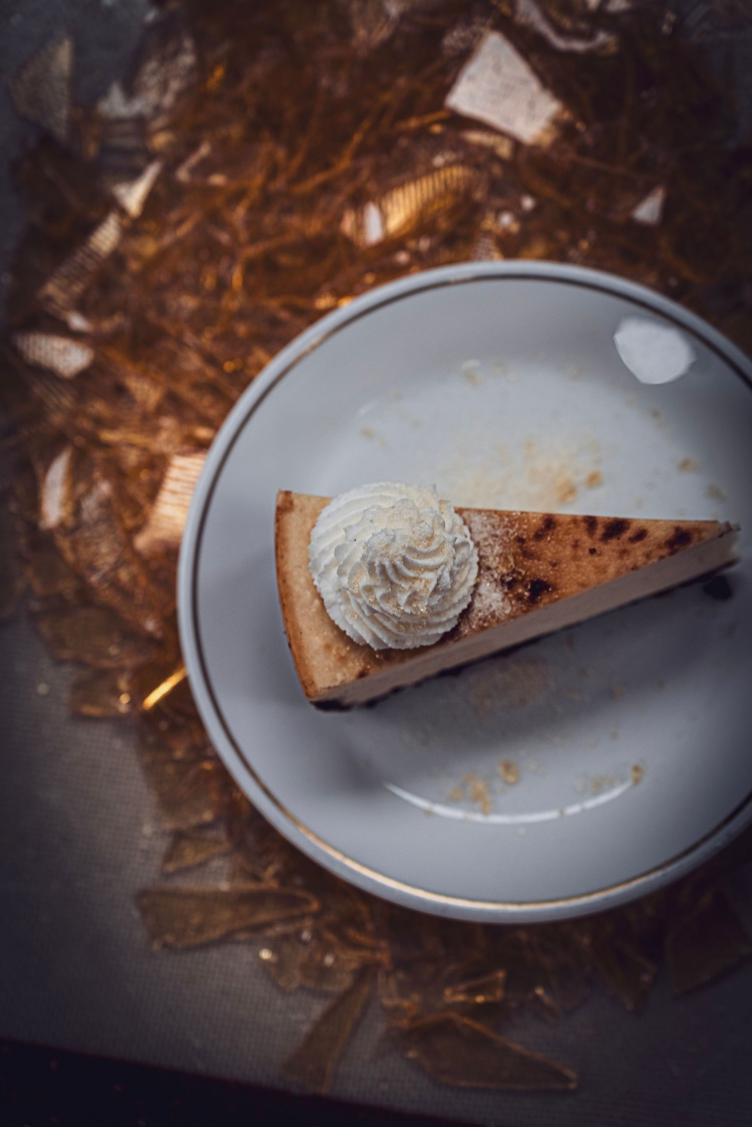A slice of pie topped with whipped cream on a gray plate against a dark textured background.