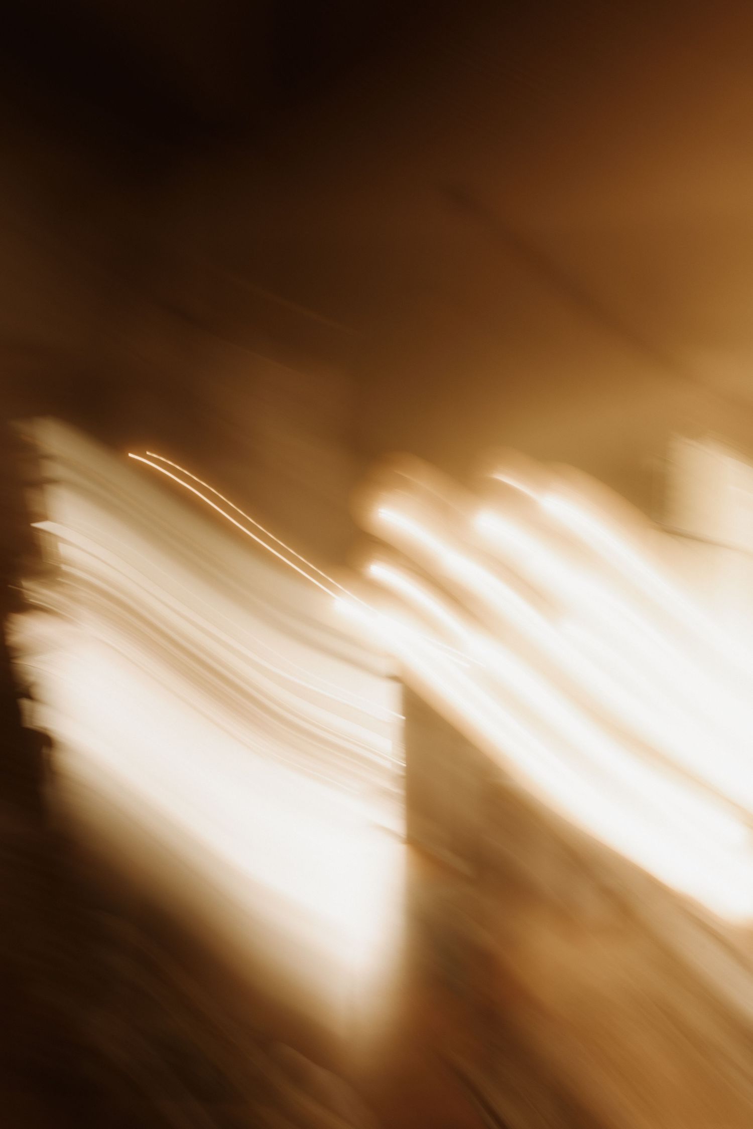 Abstract motion blur of golden light streaks against dark background, creating a dreamy, ethereal bokeh effect.