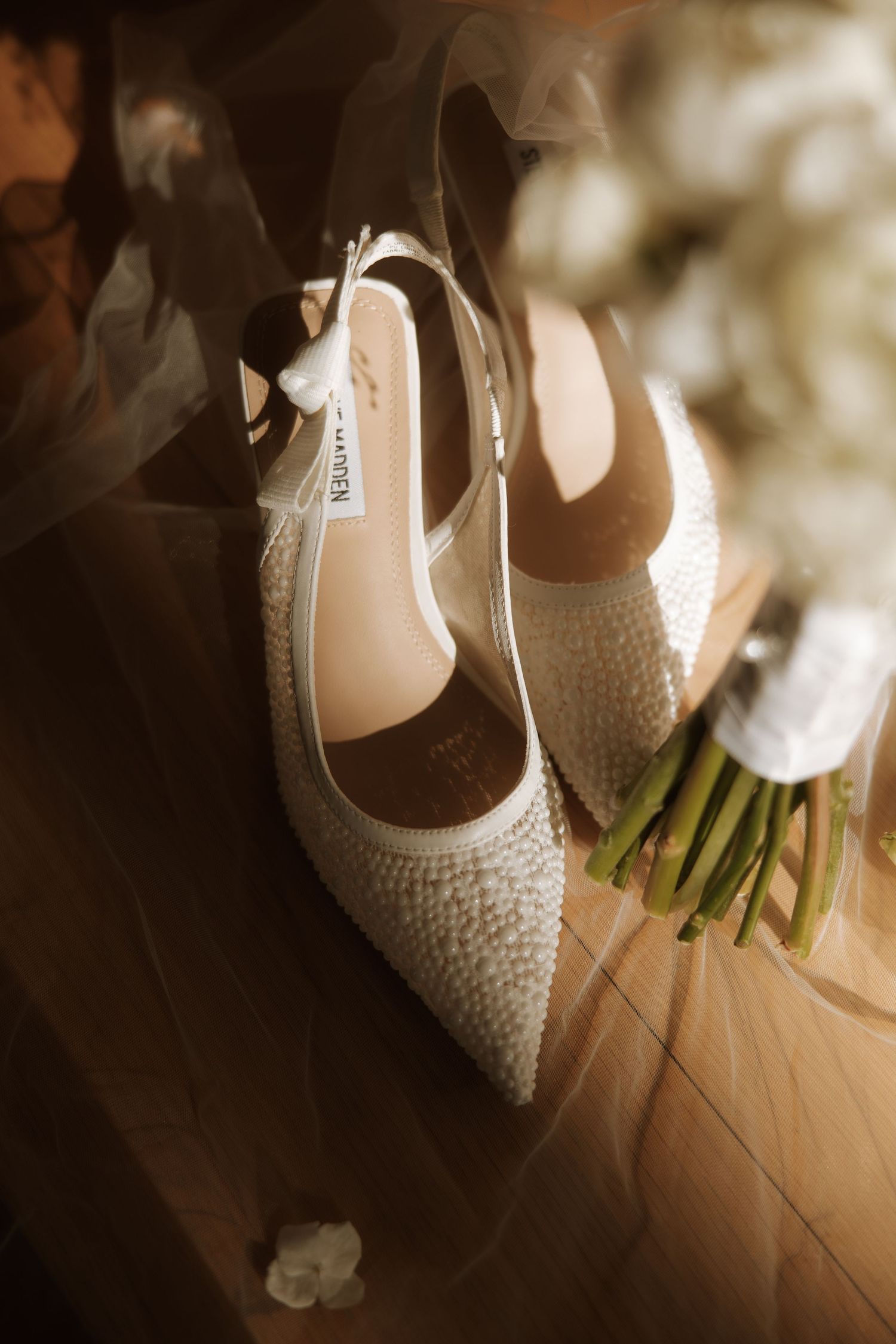 A series of wedding shoes with pearl embellishments photographed in natural light on a wooden floor.