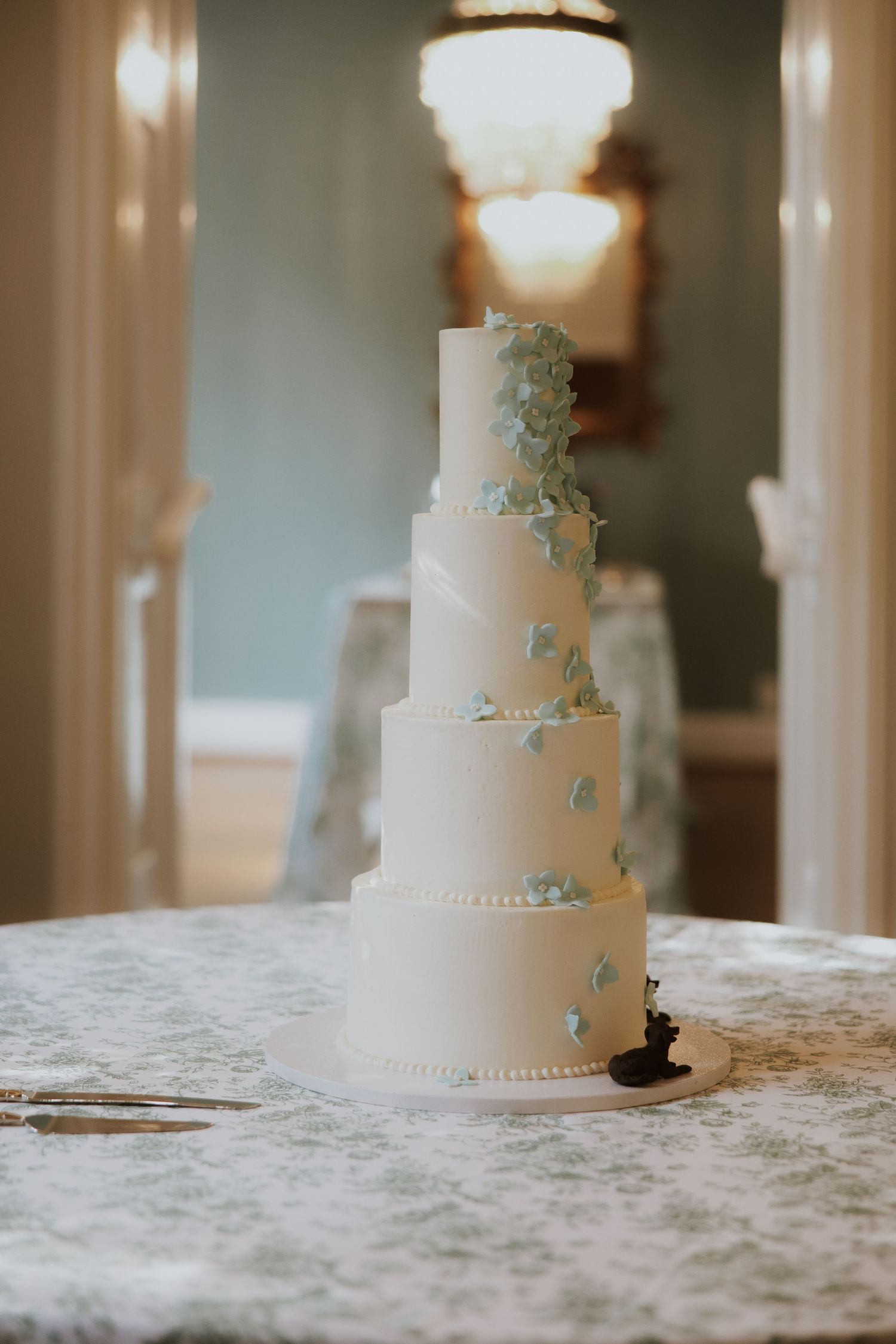 Elegant white tiered wedding cake with delicate decorative details displayed on a lace-covered table.