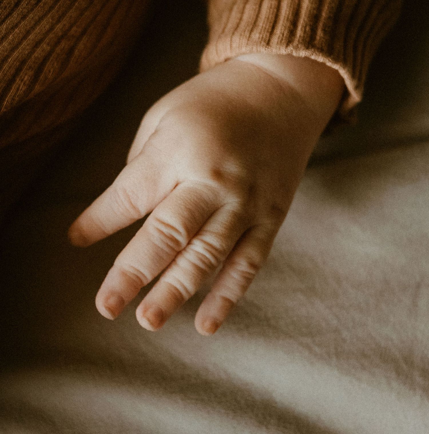 Close-up of a tiny baby's hand against a light background.