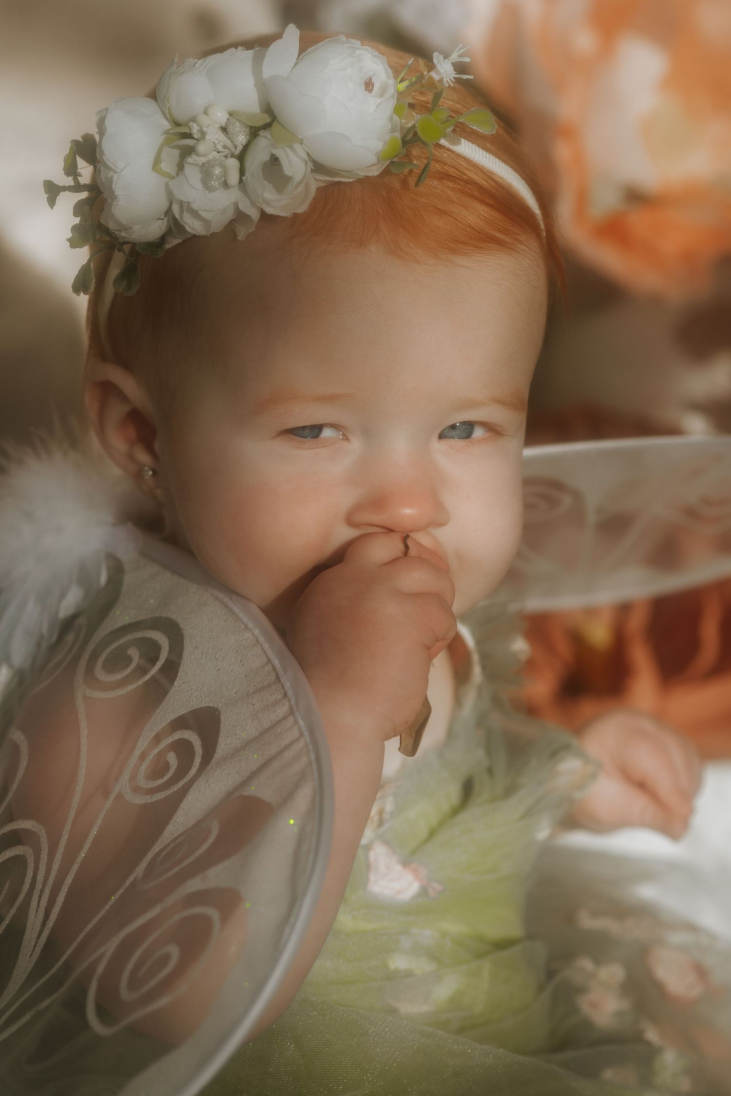 Baby wearing fairy wings and flower crown in dreamy portrait.