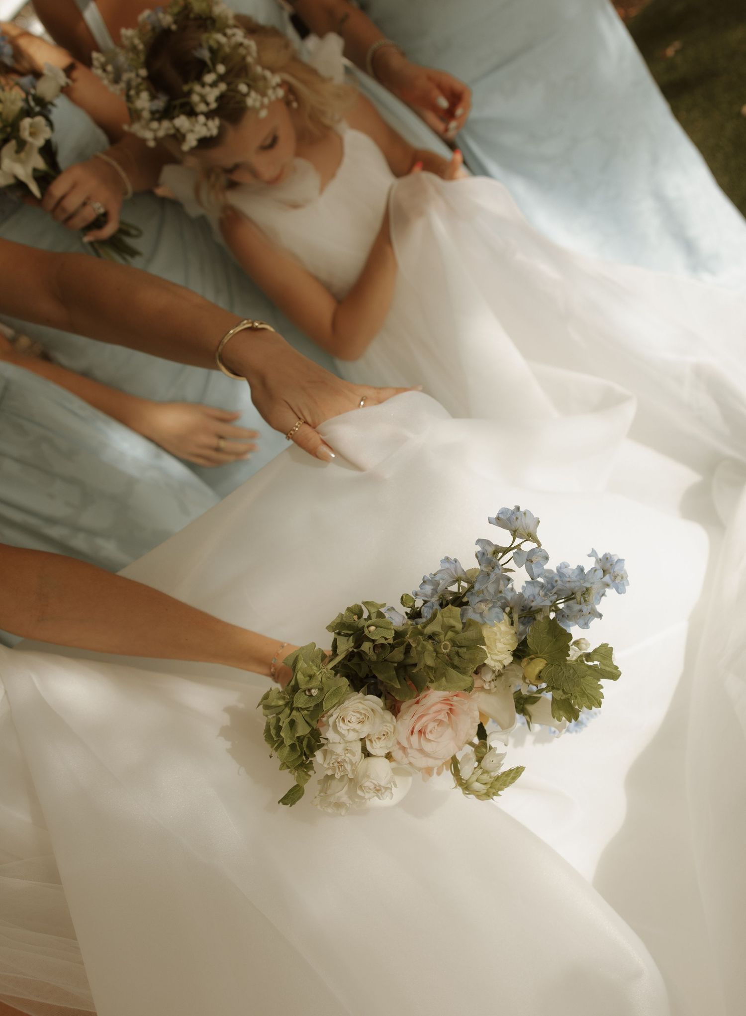A white wedding dress and floral bouquet with pink roses and greenery captured in soft natural light.