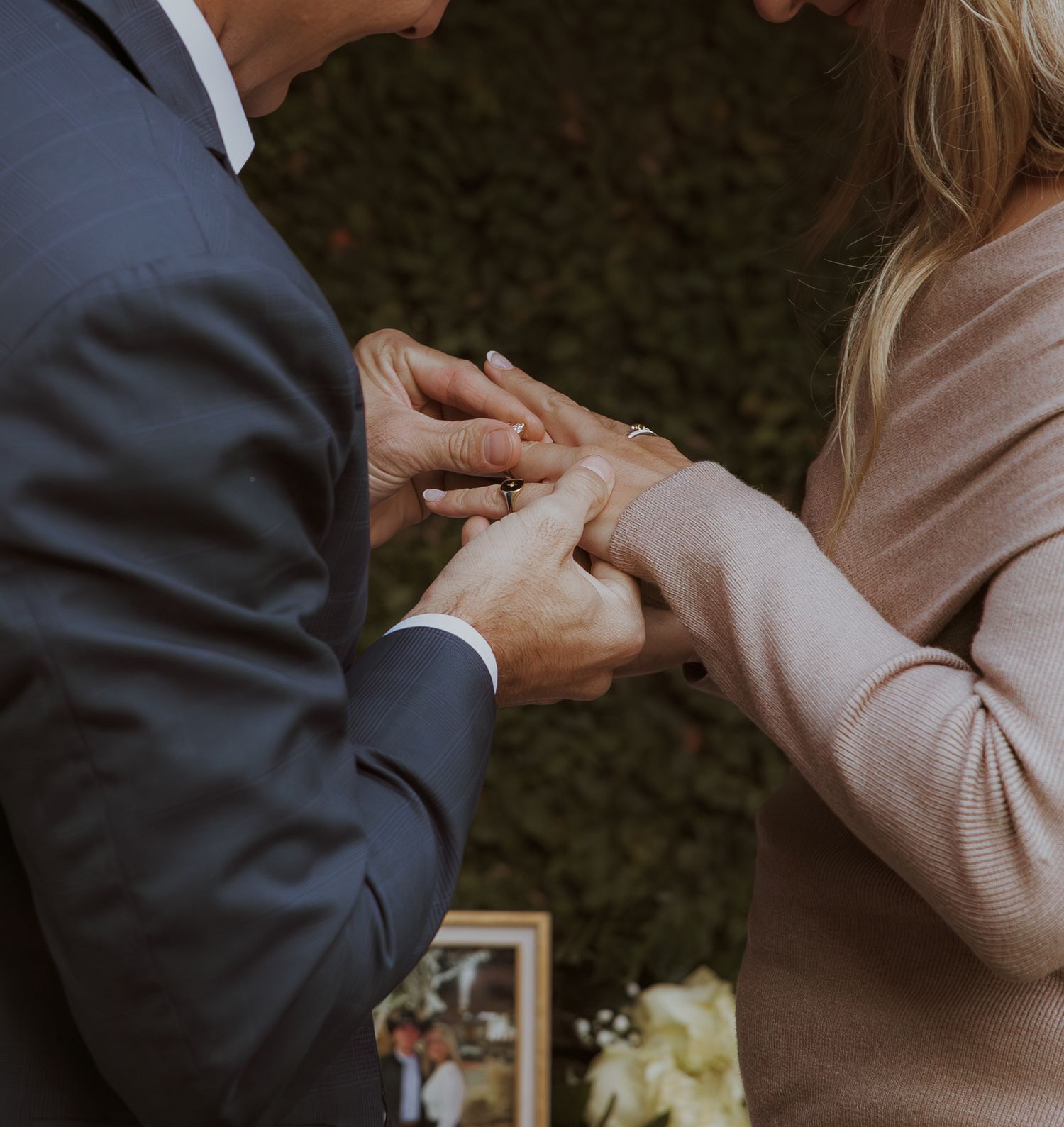 Close-up of hands during proposal moment against green foliage background.