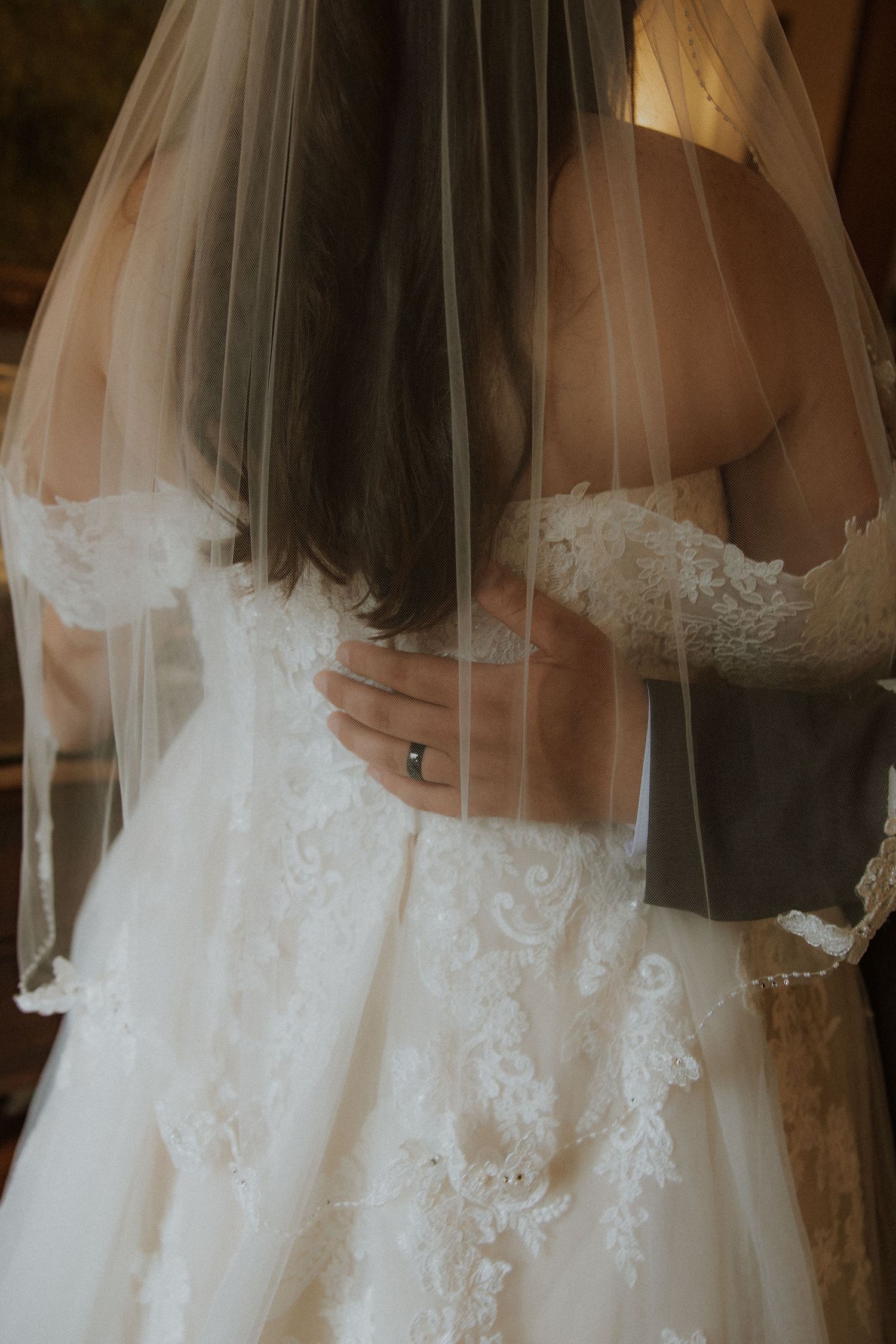 Close-up of an intricate lace wedding dress with veil detail.