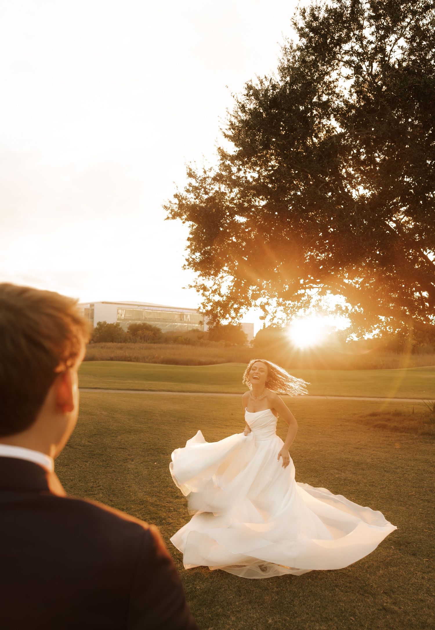 A flowing white wedding dress twirls gracefully in a golden sunset light on an open field.