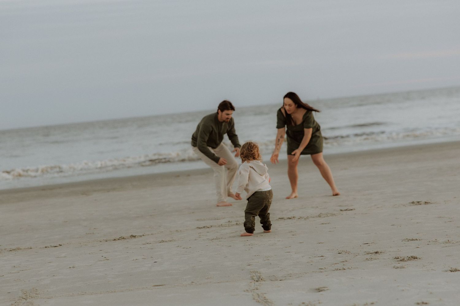 A joyful moment of a small child playing on the beach with adults.