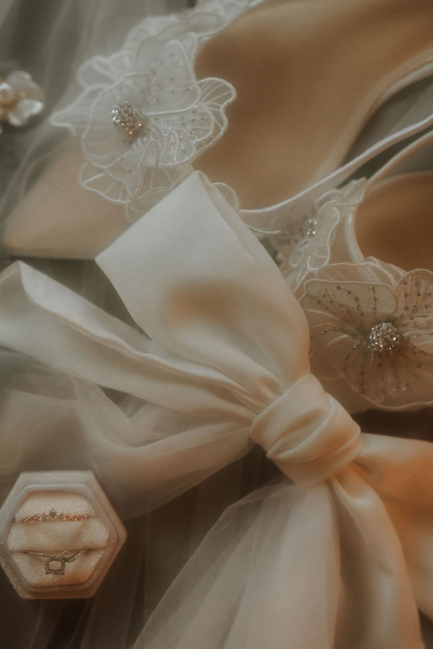 Close-up details of delicate white lace and satin fabric from a wedding dress create an elegant, ethereal composition.