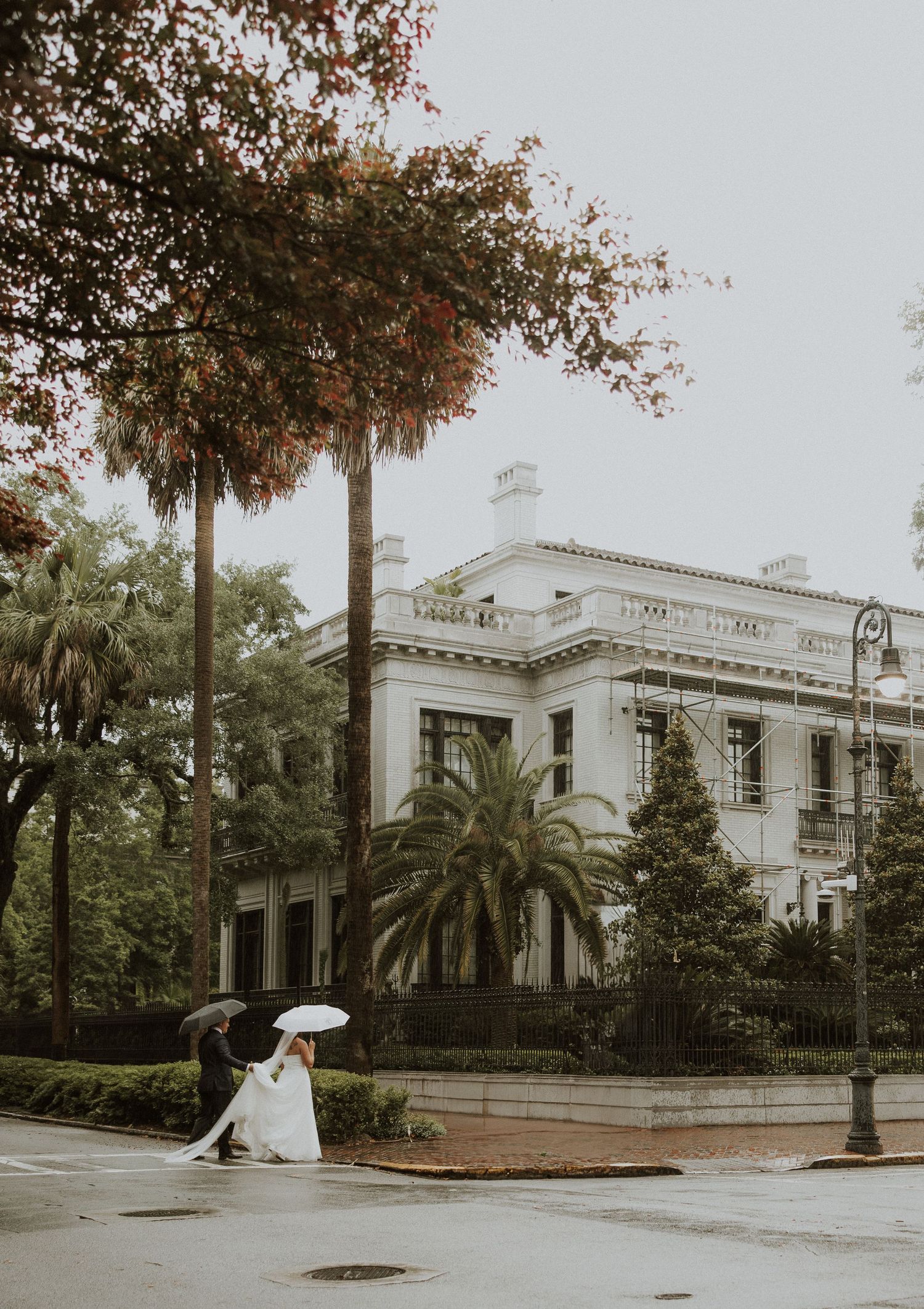 White neoclassical mansion with palm trees and iron lamp posts captured in panoramic sequence on overcast day.