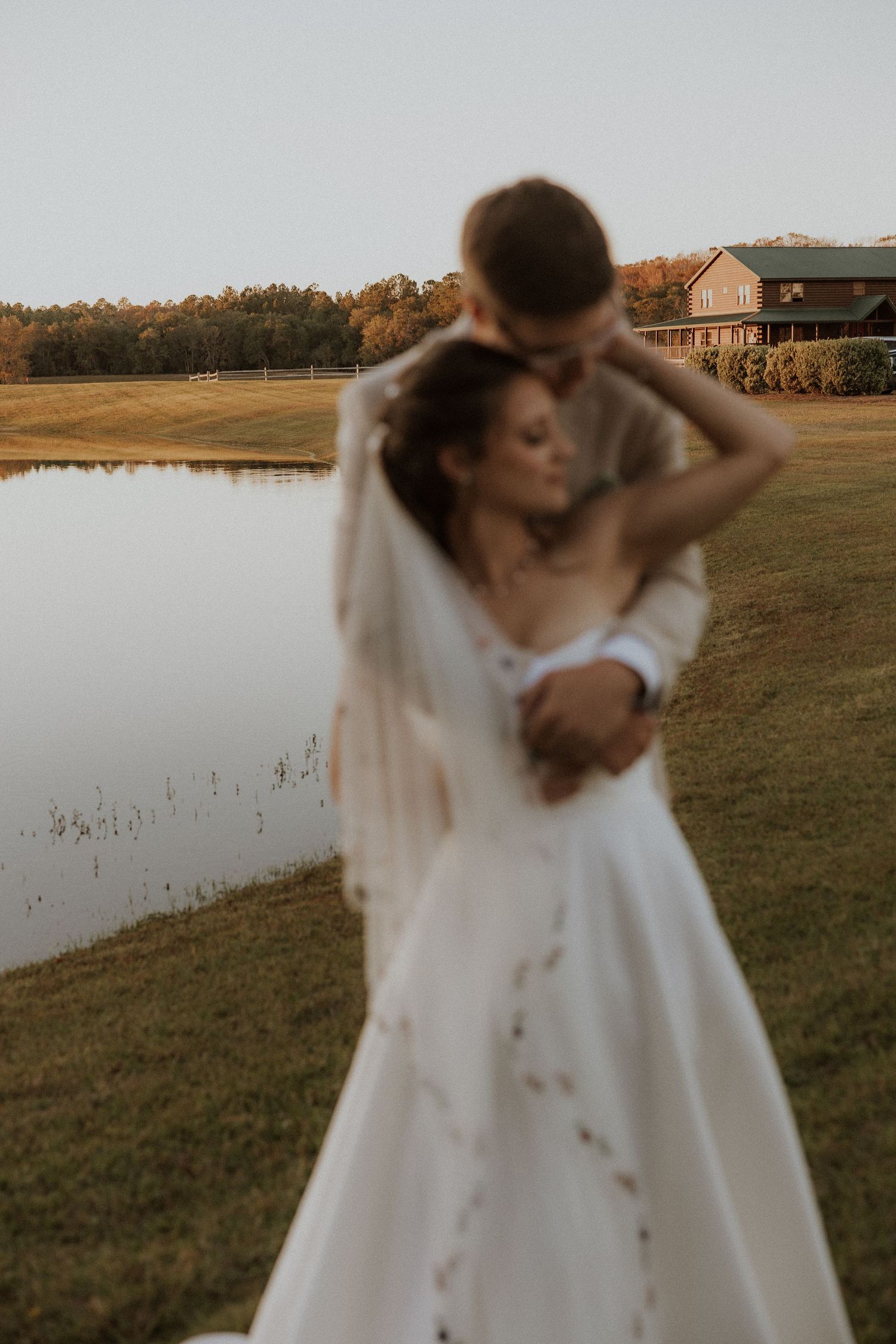 Intimate sunset wedding portrait by a tranquil pond with warm golden light.