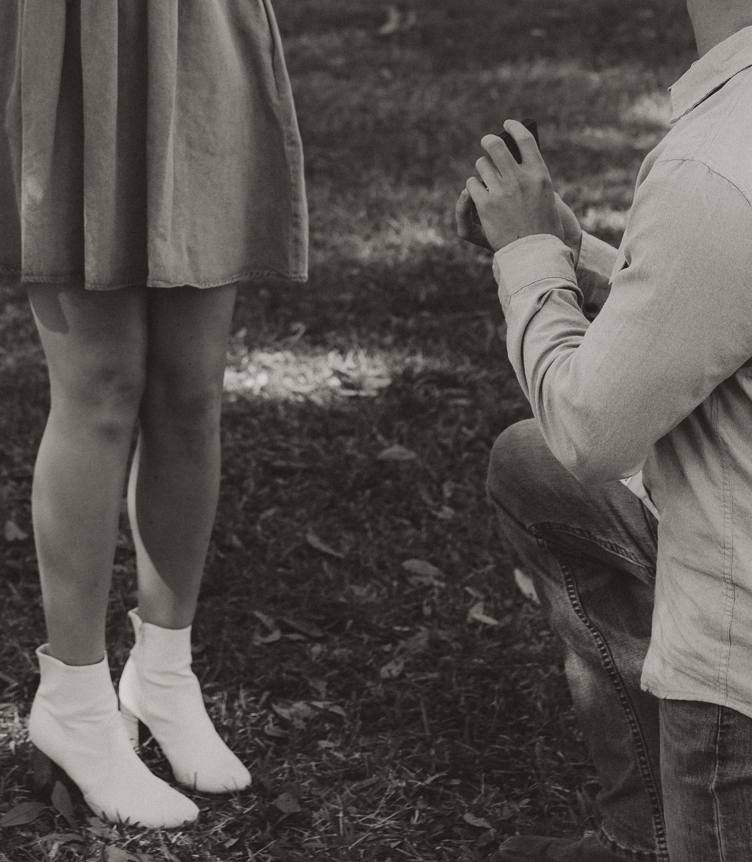 Black and white image of a proposal moment showing feet and kneeling position.
