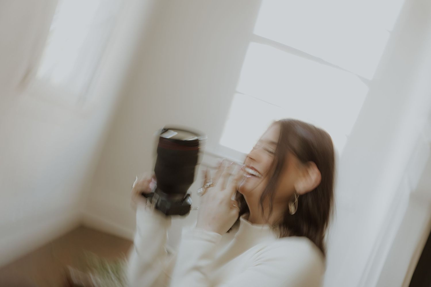 Person laughing while holding camera lens.