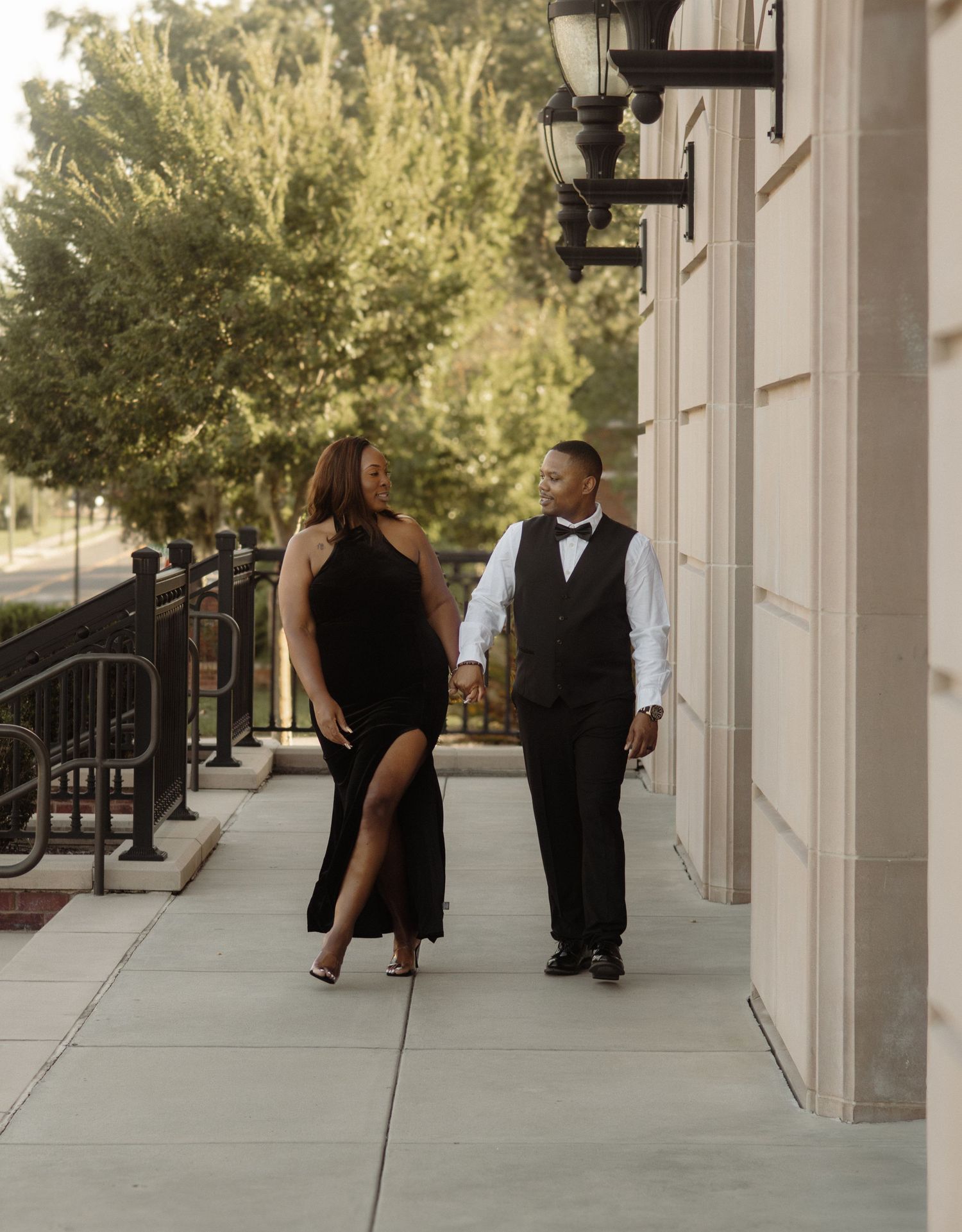 Formal couple walking along a sidewalk in elegant evening attire.