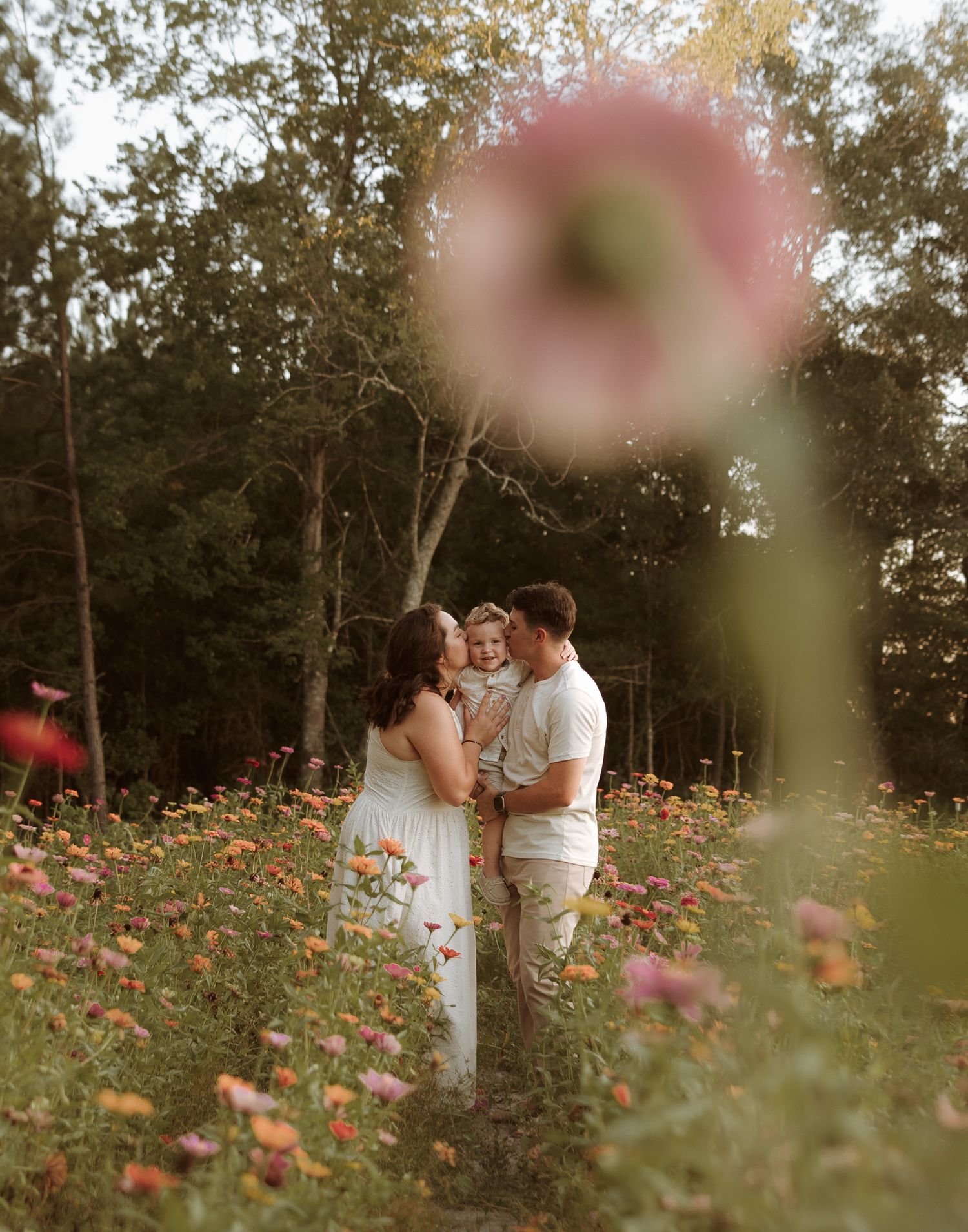 A couple shares a romantic moment in a blooming flower field during sunset.