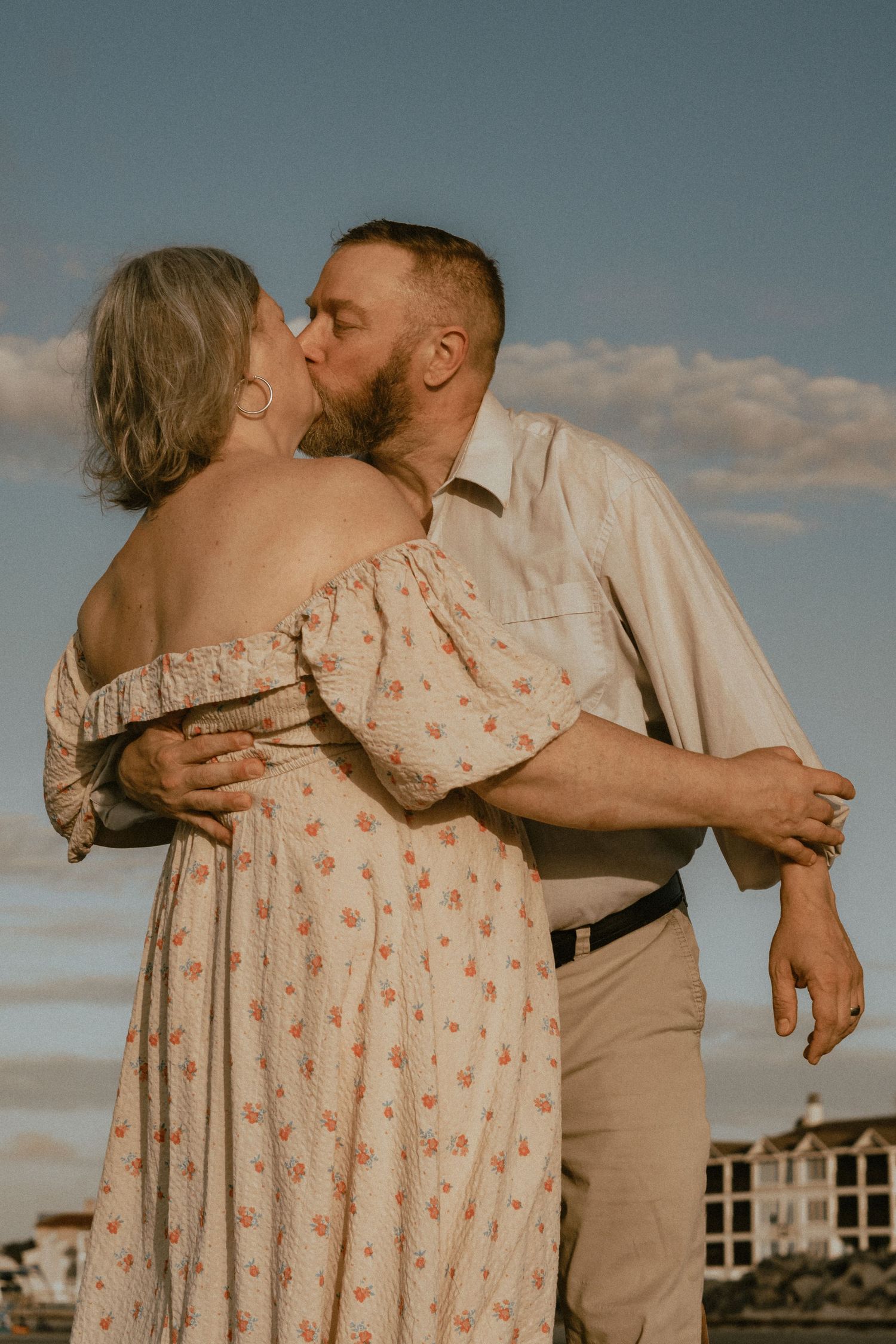 Intimate couple sharing a romantic kiss on the beach during sunset.