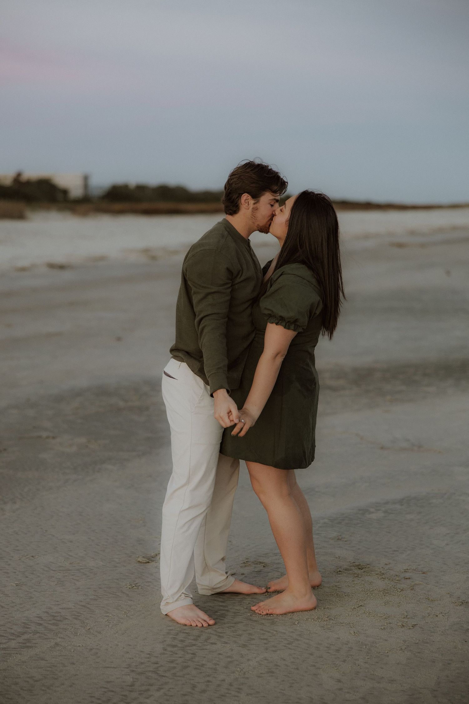 Romantic couple sharing an intimate moment on a beach at sunset.