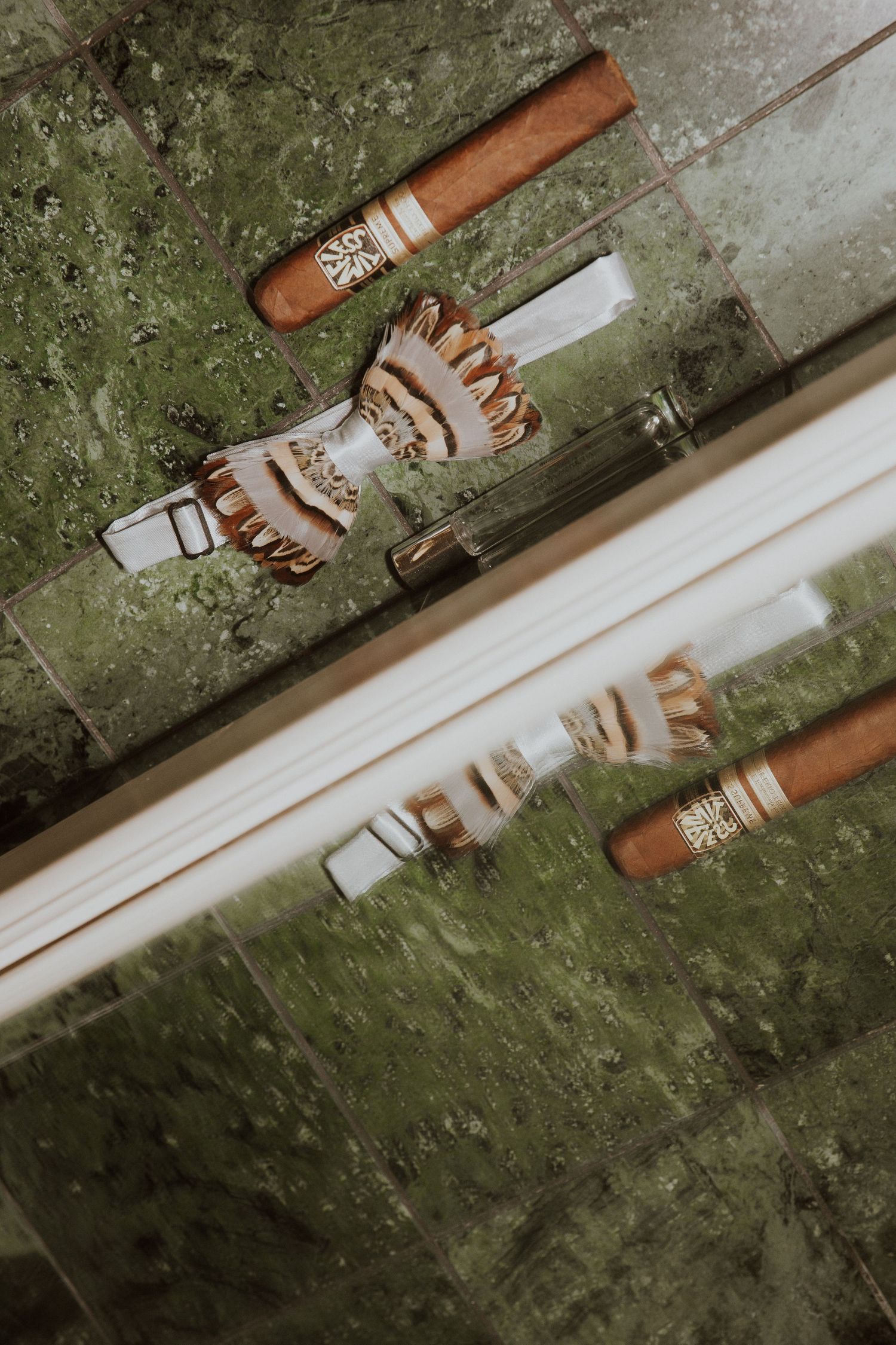 Two lit cigars with ornate decorative holders and bands against a rustic green textured background.