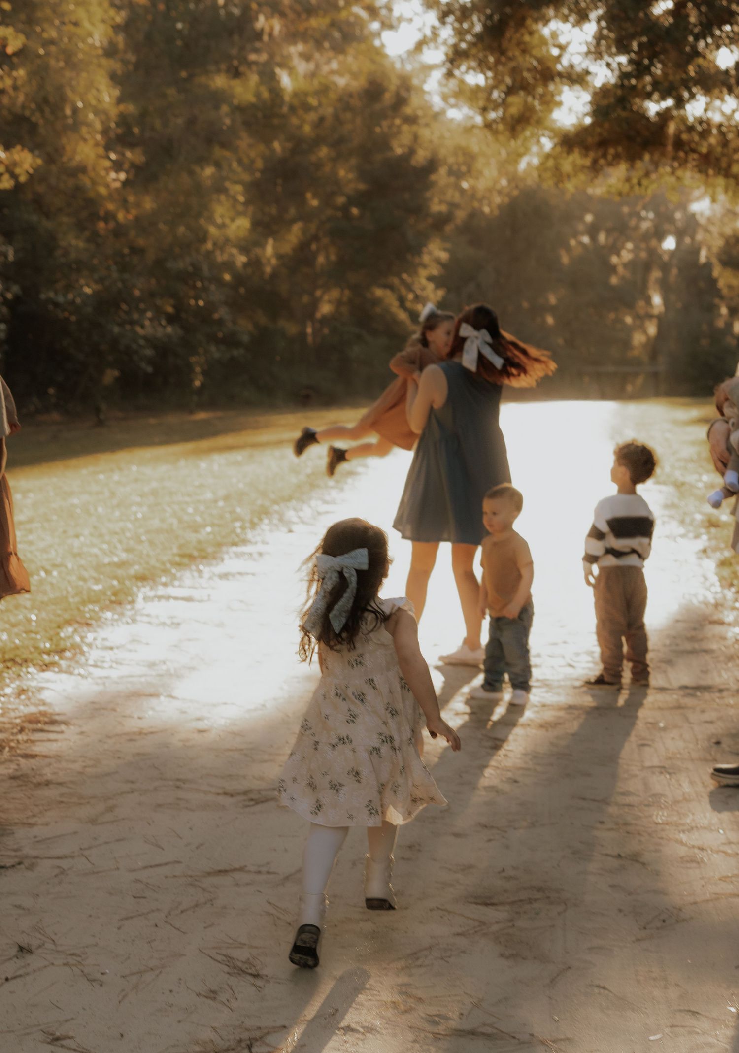Sunset photo of family playing together on dirt path in golden afternoon light.