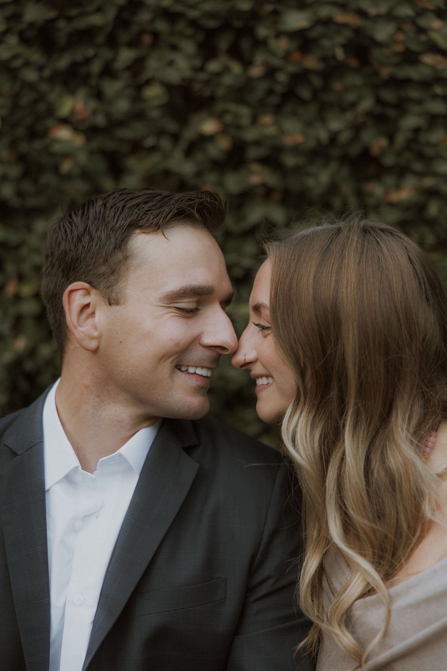 Intimate close-up of couple sharing tender moment against green foliage.
